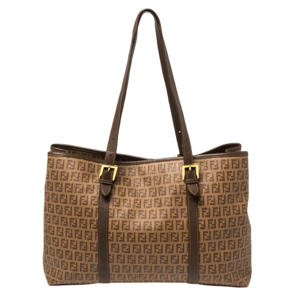 The Fendi tote is crafted from signature canvas and features leather trims, dual top handles, gold-tone hardware, and a spacious interior sized to hold all your daily essentials. Highly functional and instantly luxurious, it is a creation worth