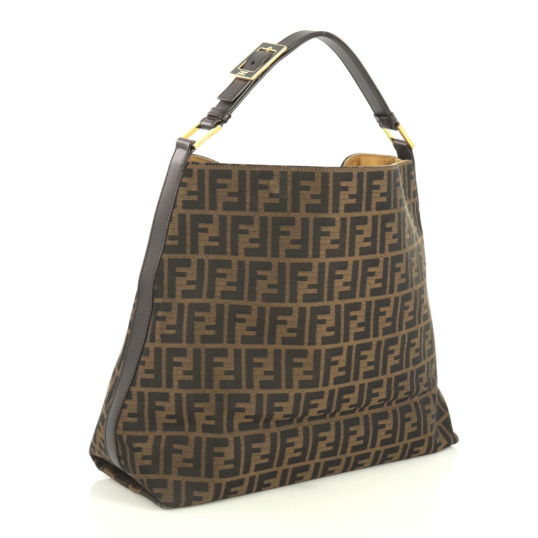 This Fendi Buckle Strap Hobo Zucca Canvas Large, crafted from brown zucca canvas, features an adjustable buckled shoulder strap, leather trim and gold-tone hardware. Its wide open top showcases a neutral fabric interior with zip pocket. 

Estimated
