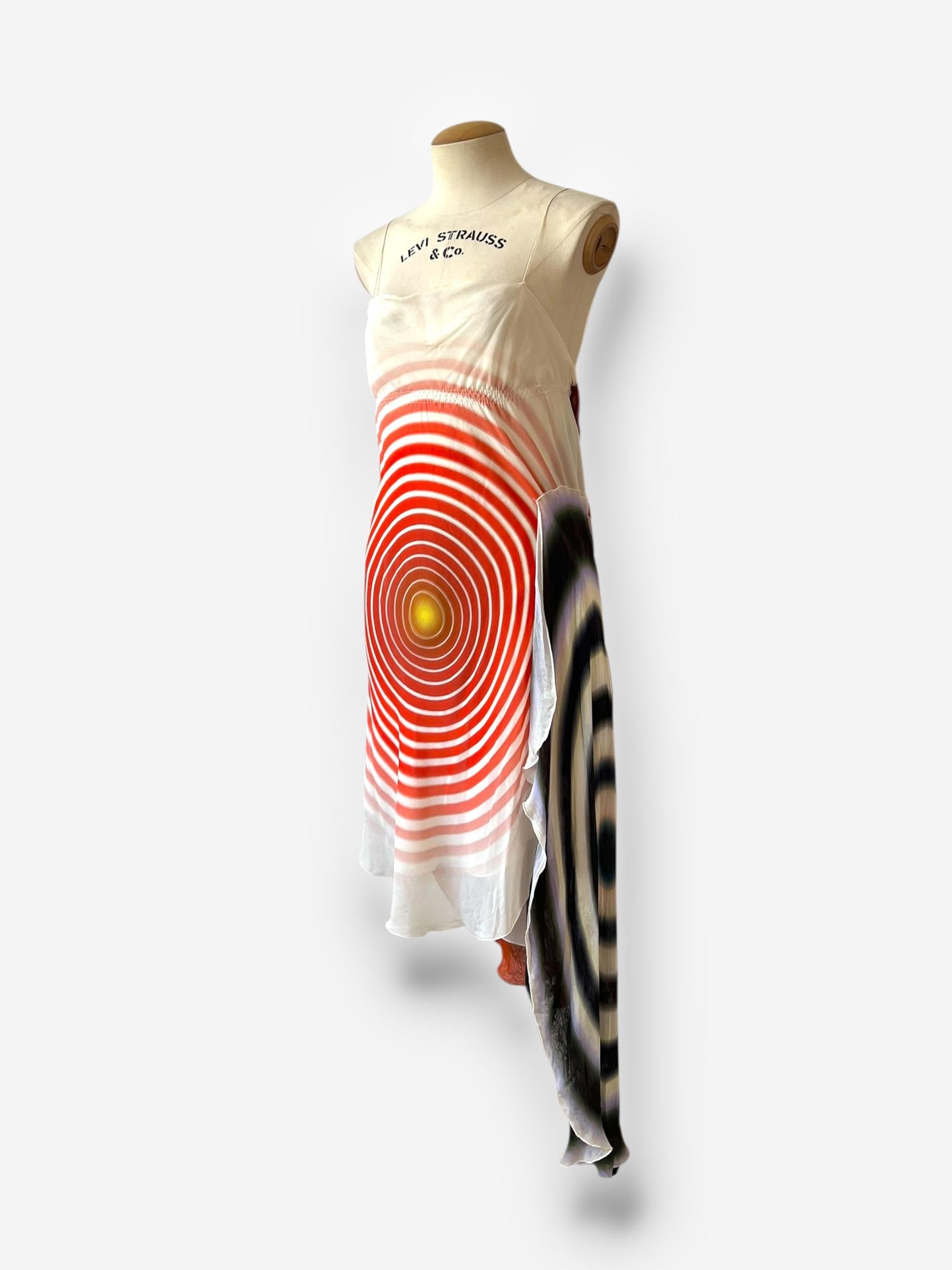 

This striking Fendi dress from 2008, designed by the legendary Karl Lagerfeld, showcases a bold abstract circular graphic print in vibrant shades of orange, red, yellow, black, and white. Crafted from lightweight silk, the dress flows elegantly