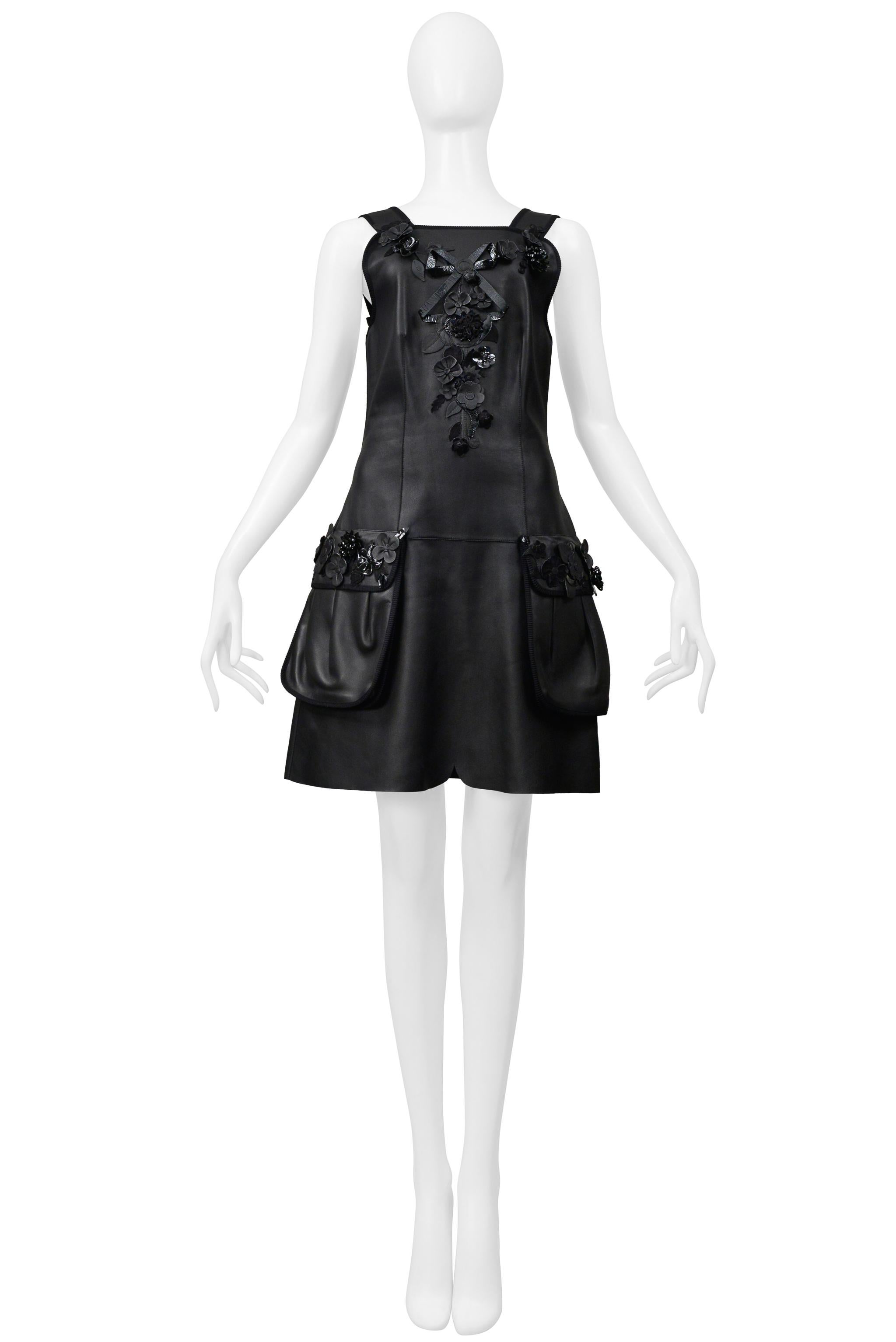 Resurrection Vintage se complace en ofrecer un vestido vintage Fendi by Karl Lagerfeld de cuero negro con tirantes de cuero negro con ribetes, cuero decorativo y flores de charol en el corpiño, bolsillos y tirantes, bolsillos delanteros, cremallera