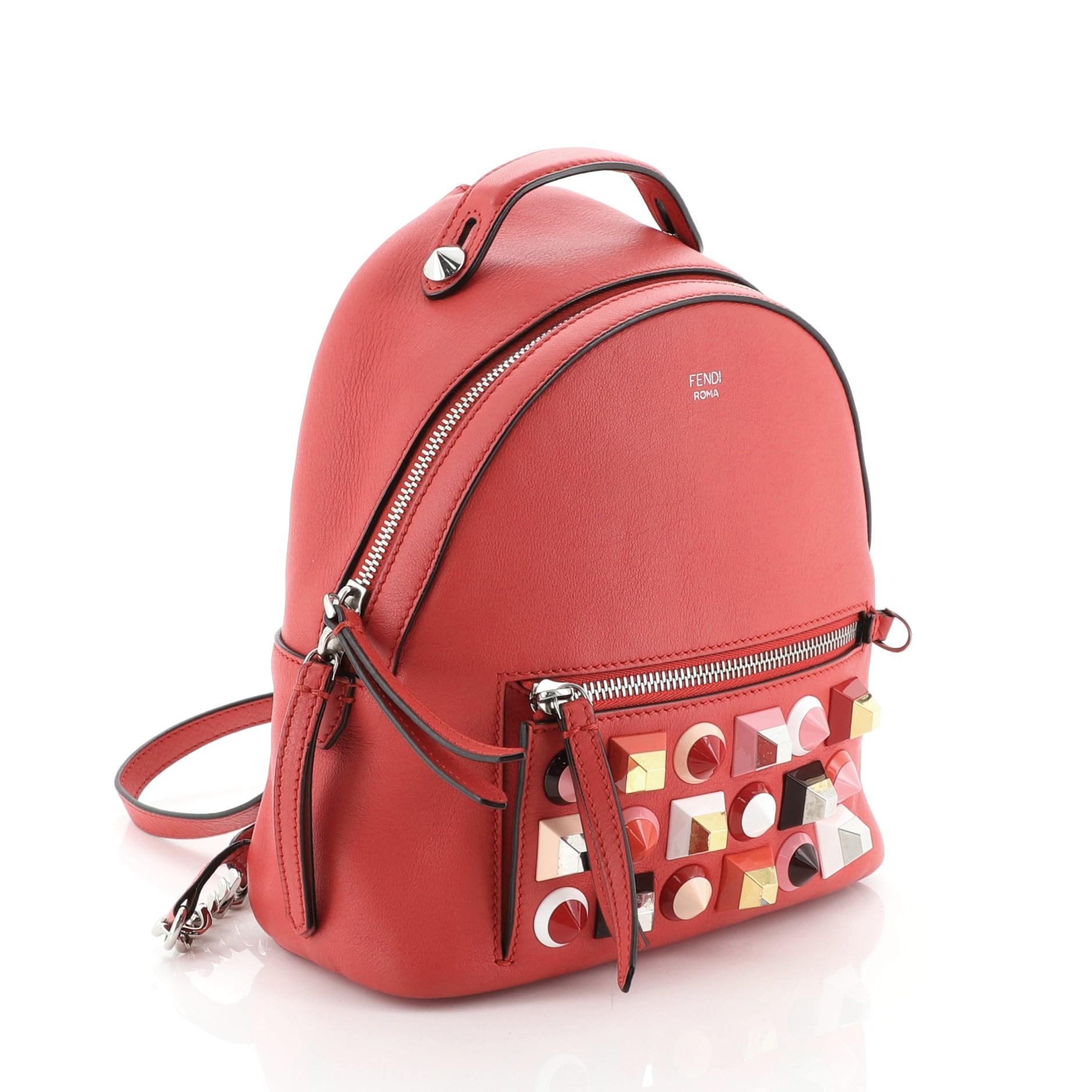 This Fendi By The Way Backpack Studded Leather Mini, crafted in red leather, features oversize studs, leather top handle, adjustable leather straps, exterior front zip pocket and silver-tone hardware. Its zip closure opens to a black fabric interior
