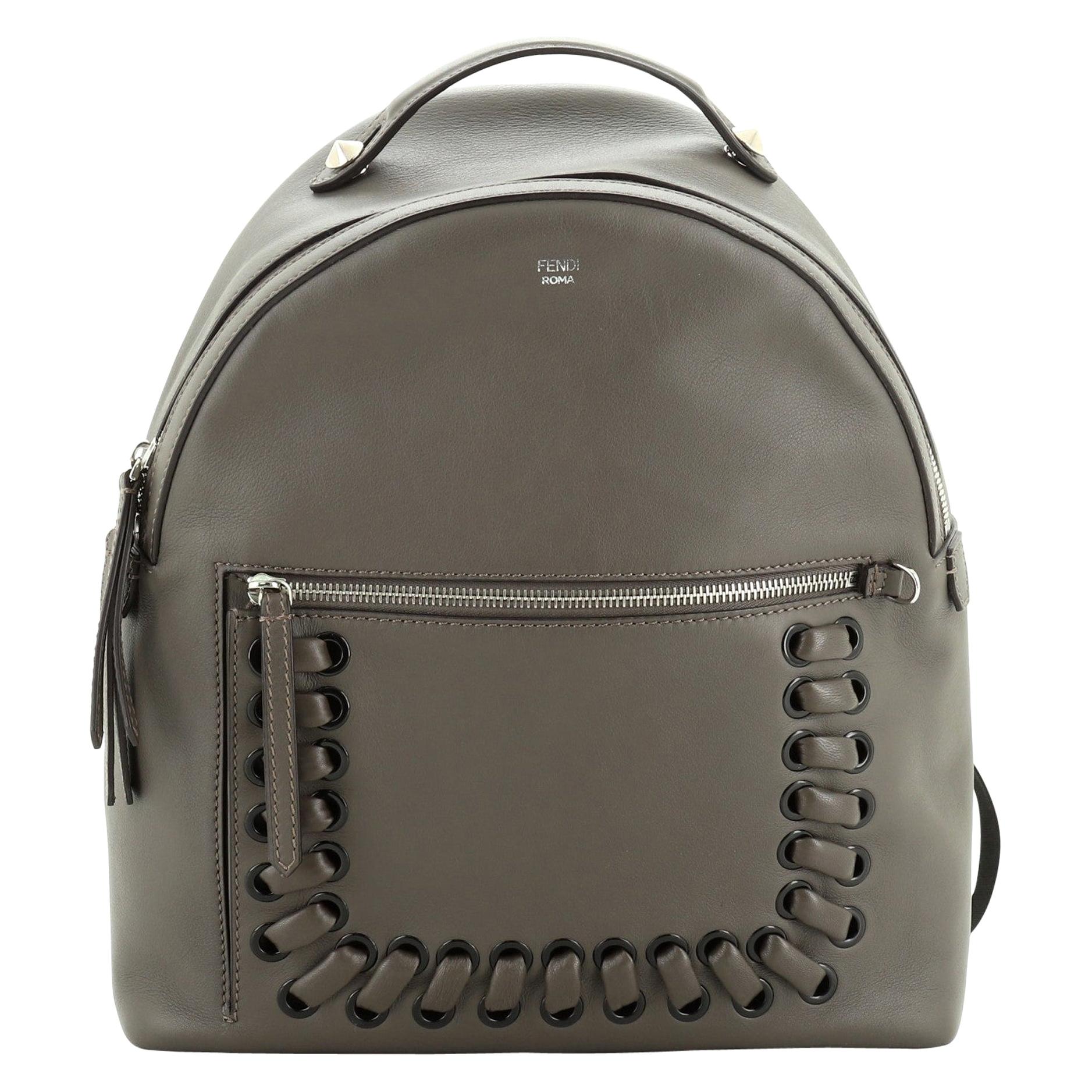 This Fendi By The Way Backpack Whipstitch Leather Medium, crafted in neutral leather, features leather top handle, adjustable leather straps, exterior front zip pocket, whipstitch details, and silver-tone hardware. Its zip closure opens to a gray