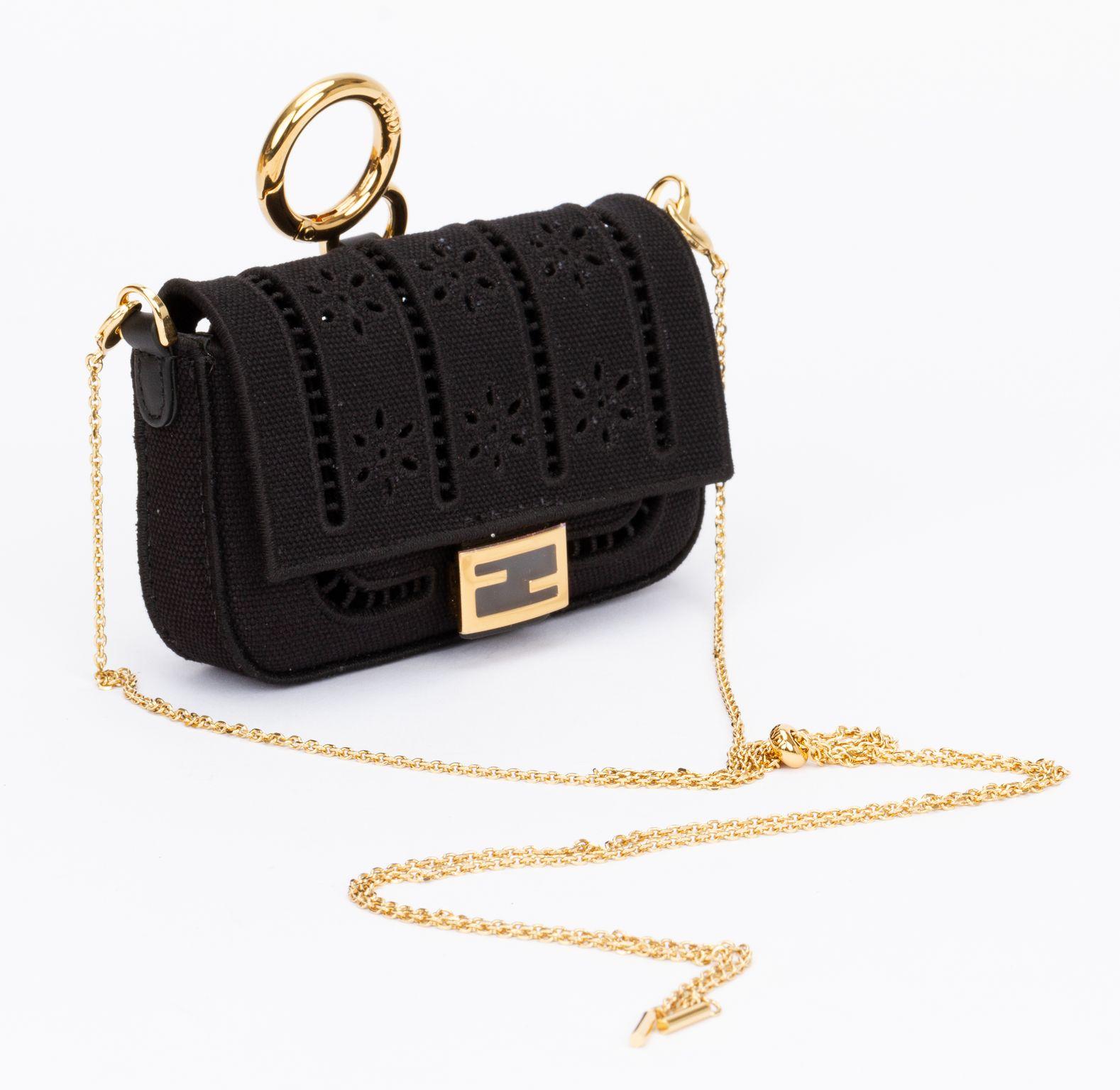 Fendi canvas embroidered nano baguette in black. The nano charm is made of black perforated canvas. It can be attached to a belt or clipped on to a bigger bag or it can be worn crossbody with the polished gold chain shoulder strap. (drop up to 19
