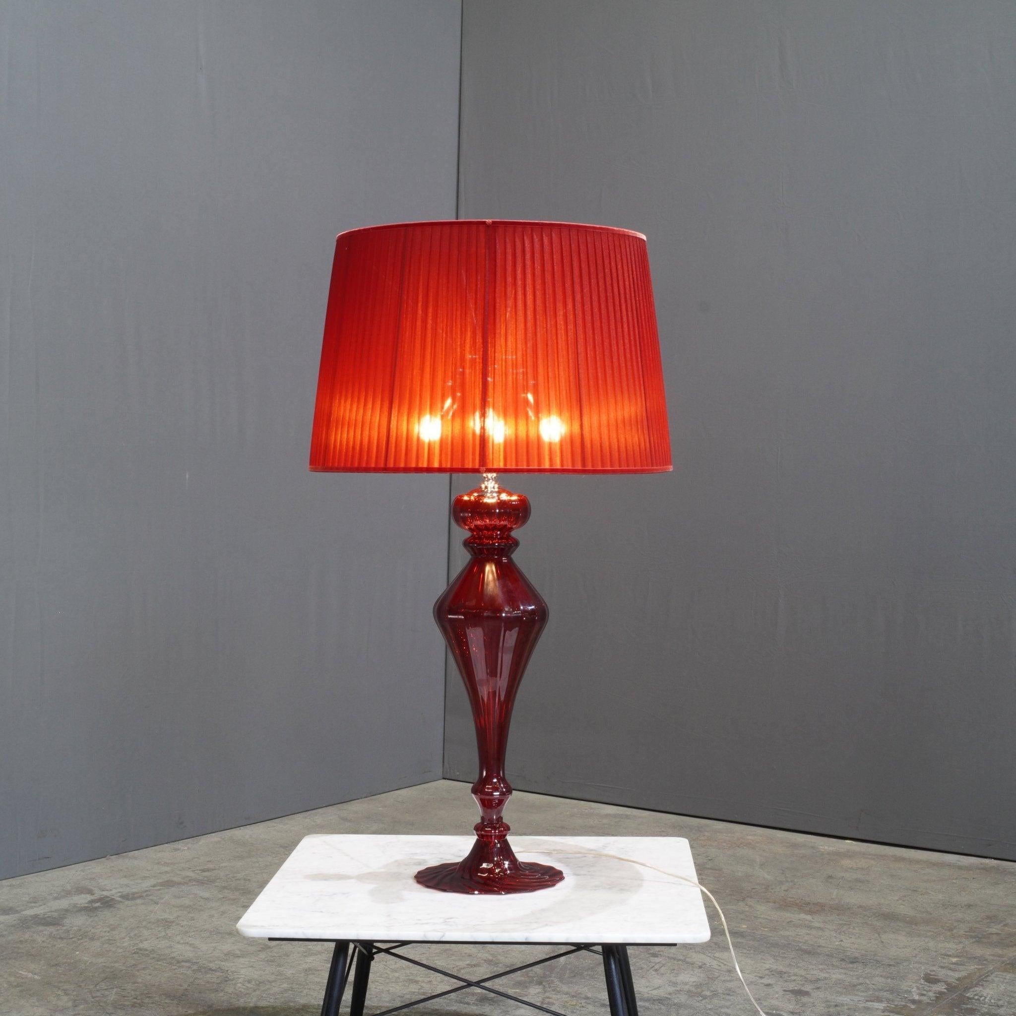 The Fendi Casa Red Murano Table Lamp is a striking blend of luxury and Italian craftsmanship. This exquisite piece features a vibrant red Murano glass base, embodying the timeless elegance associated with Venetian glassmaking. The sculptural quality