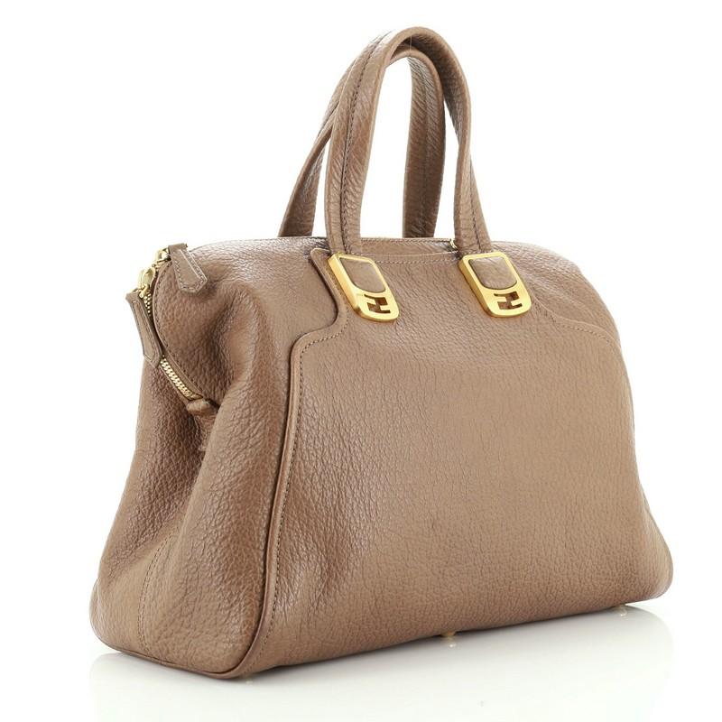 This Fendi Chameleon Convertible Satchel Leather Large, crafted in brown leather, features dual top handles accented with FF logo hardware, protective base studs, and gold-tone hardware. Its two-way zip closure opens to a neutral fabric interior