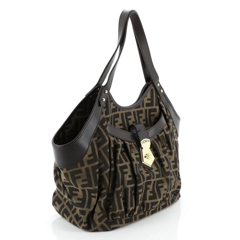 This Fendi Chef Pocket Tote Zucca Canvas Medium, crafted from brown zucca canvas with chocolate brown leather trims, features dual leather handles and gold-tone hardware. The top zip closure opens to a brown fabric interior. 

Condition: Very good.