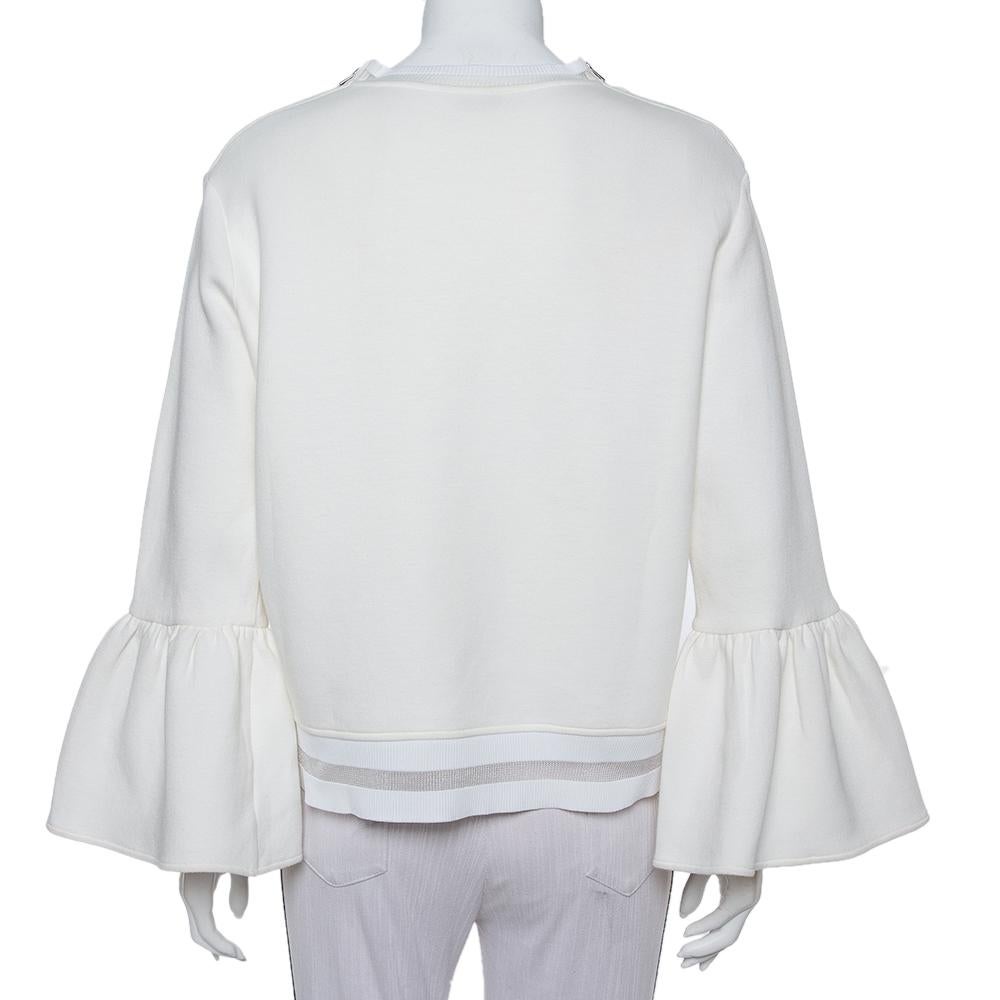 Este jersey Fendi es una creación femenina que puede combinarse con un montón de pantalones. Fabricado con materiales de calidad, este jersey de color crema tiene apliques de pompones en la parte delantera. Tiene mangas largas acampanadas, escote