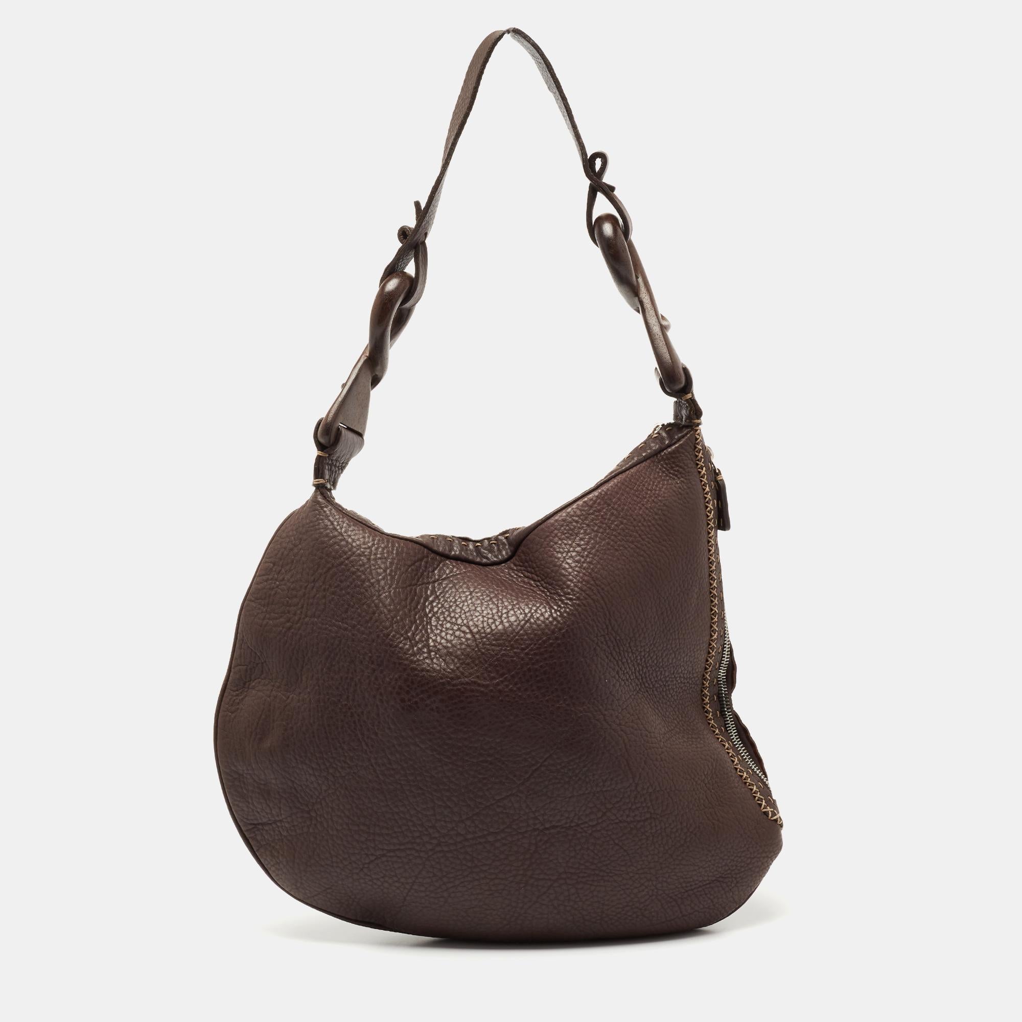 Designed for your convenience, this Fendi hobo is versatile and chic. Its brown leather exterior is decorated with an oyster web stitching detail, and it is held by a single handle at the top. Lined with suede, it is secured by a top and side zipper
