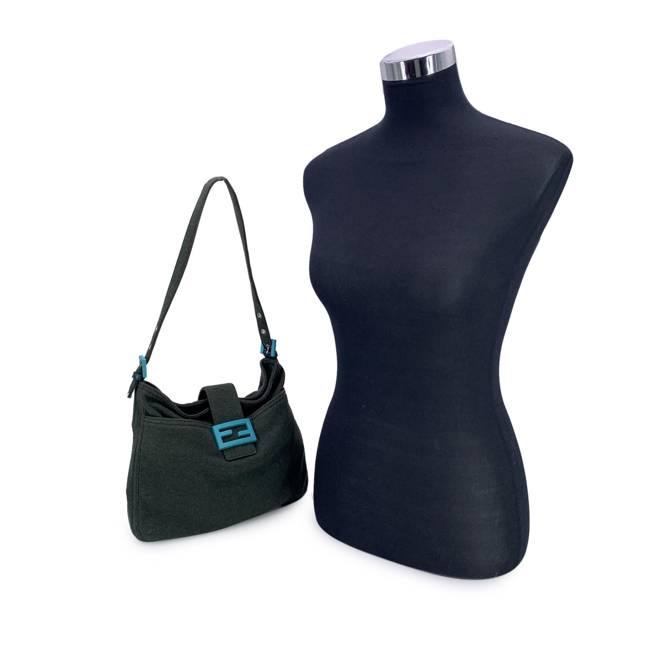 Ce magnifique sac Fendi Mama, également connu sous le nom de Mamma Baguette, est une pièce remarquable confectionnée dans un luxueux tissu semblable à de la laine, d'un vert foncé profond. Le design est rehaussé par un logo FF turquoise frappant sur