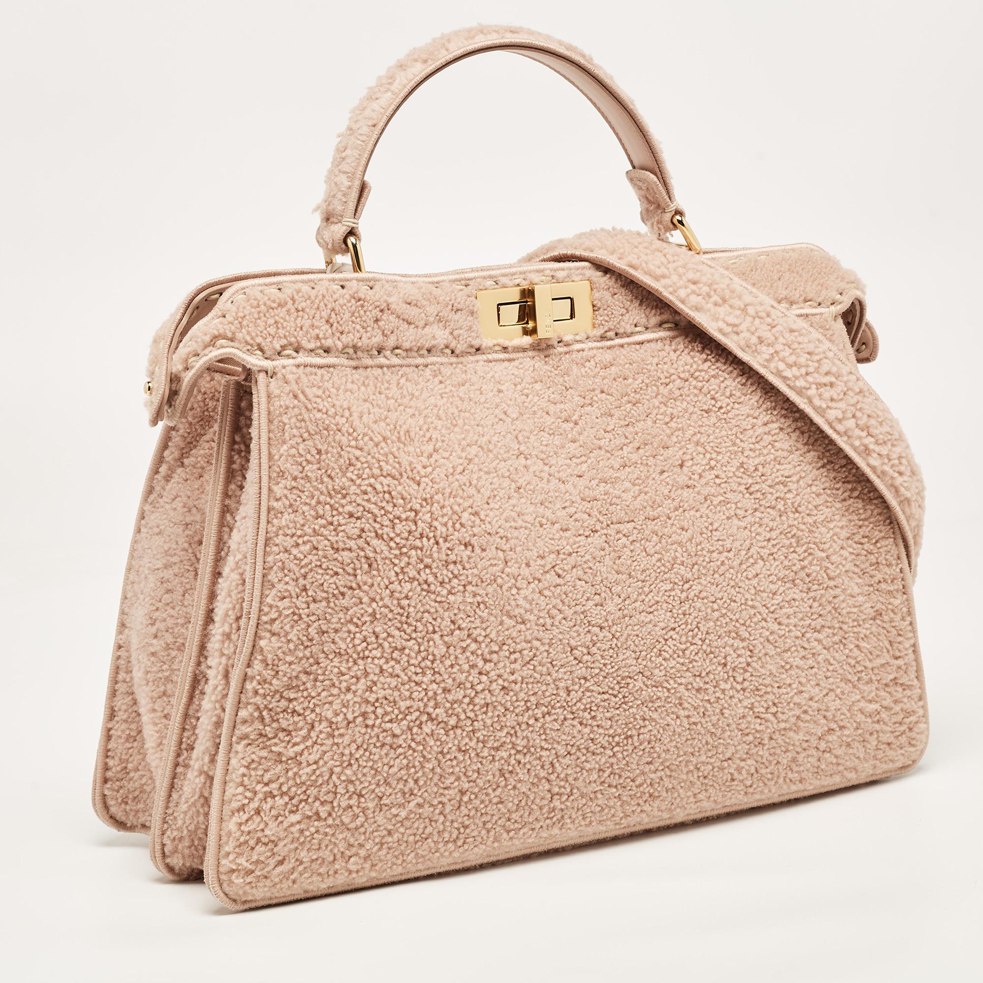 Die Fendi Peekaboo ISeeU Tasche strahlt mit ihrem plüschigen Shearling-Außenmaterial in einem raffinierten, staubigen Rosaton Luxus aus. Das kultige Peekaboo-Design wird durch einen geräumigen Innenraum aufgewertet, und ein Griff an der Oberseite