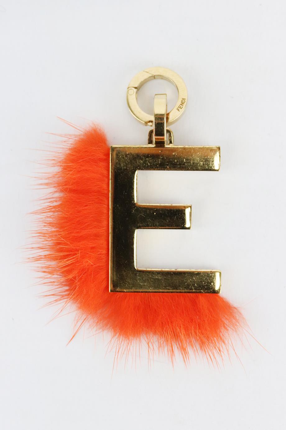 Fendi E initial gold plated bag charm. Made from gold-plated brass and pink min-fur in a E shape. Gold and orange. Clasp fastening at top. Does not come with box or dustbag. Height: 1.2 in. Width: 0.9 in