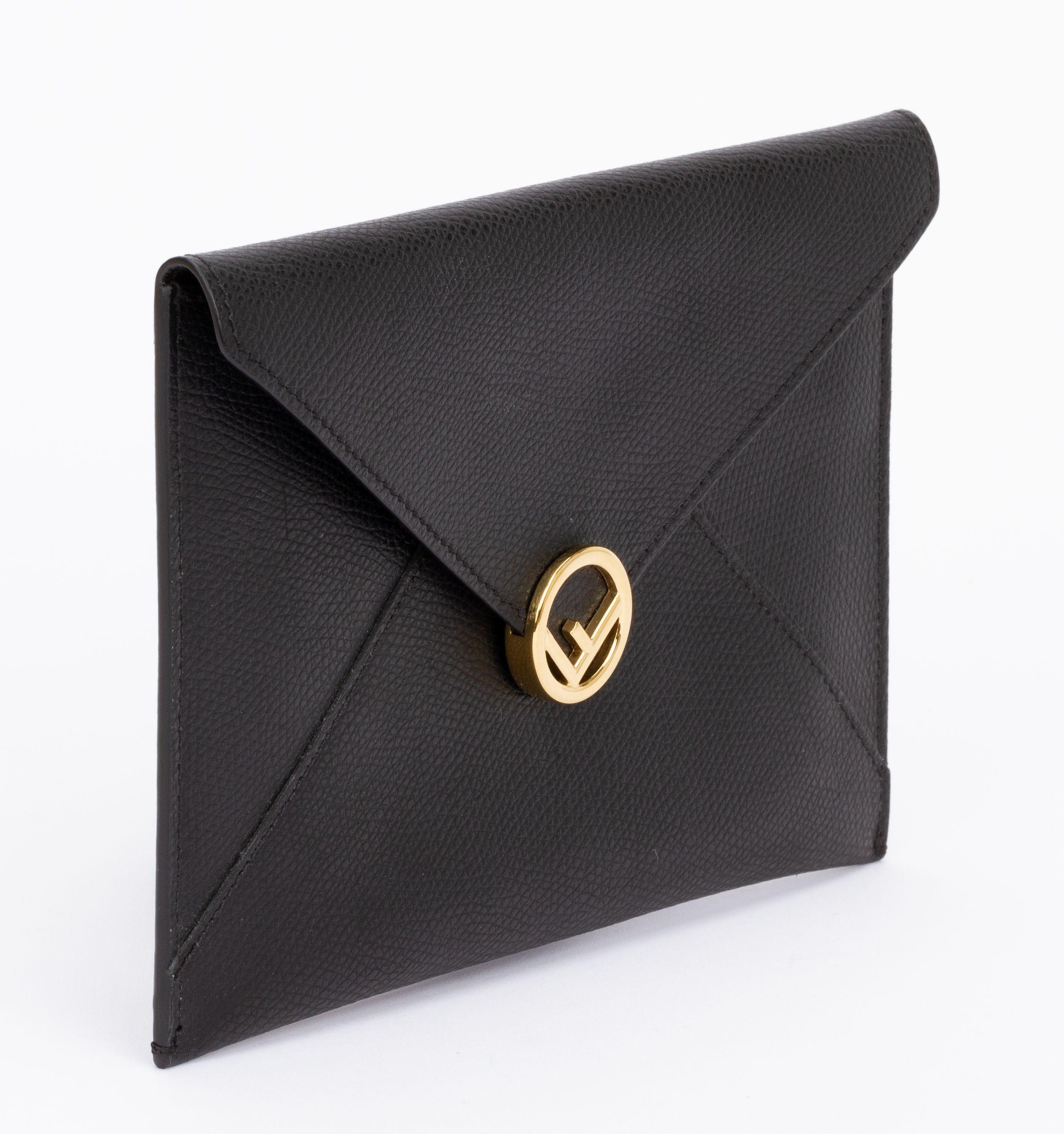 Fendi Calfskin medium flat envelope pouch in black. This pouch is made of textured calfskin leather. The top envelope flap snaps open to a matching leather interior. It closes with a push button which is gold and shows a circled F. The piece is new