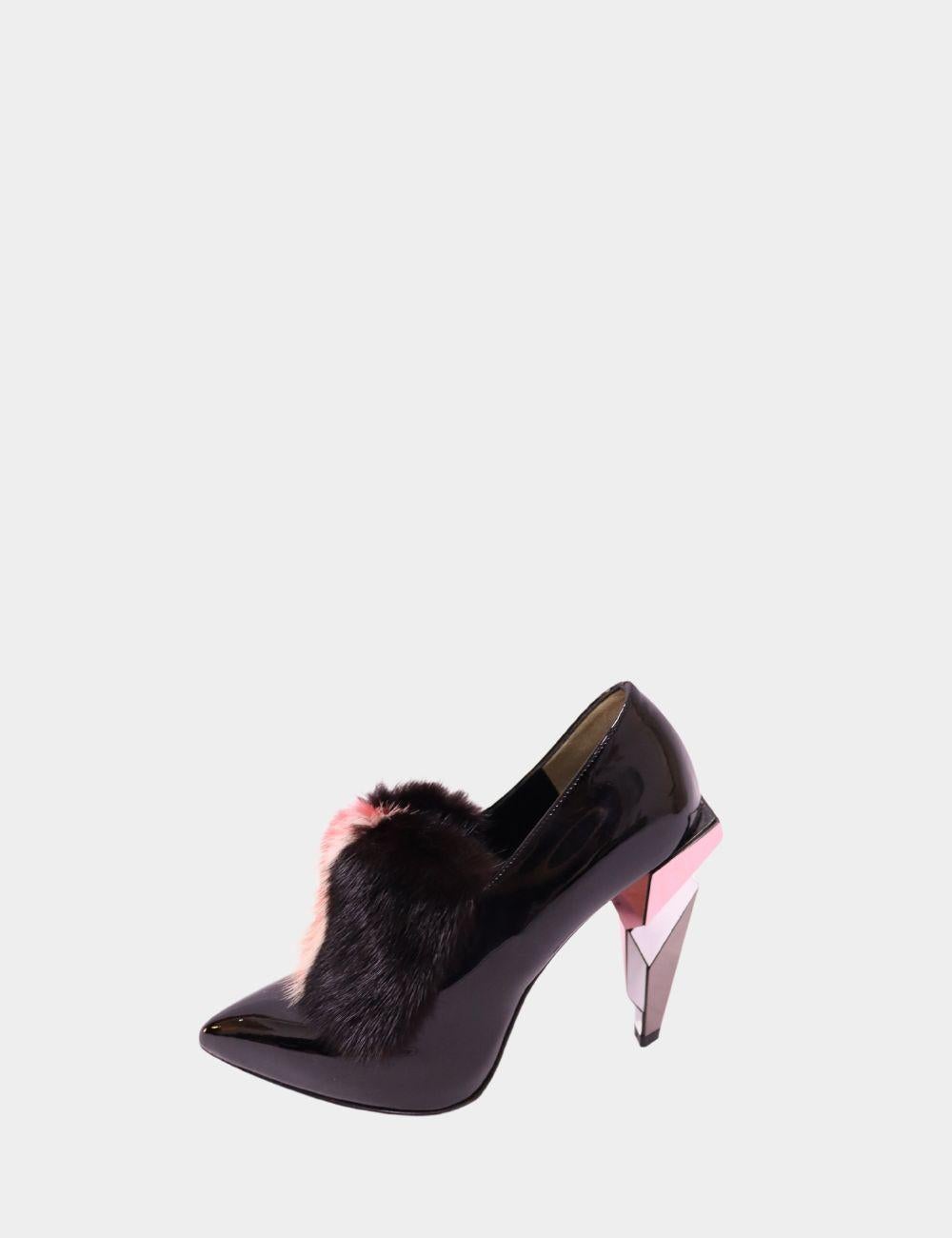 Atrae todas las miradas con estos mocasines de piel de charol negro de Fendi, una declaración lúdica y arquitectónica de la icónica casa de moda italiana. Fabricados con un acabado de charol brillante y una atrevida punta puntiaguda, estos zapatos