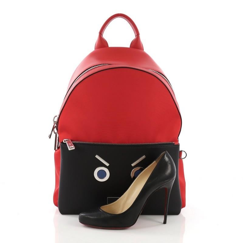 This Fendi Faces Backpack Nylon and Leather, crafted from red nylon and black leather, features leather top handle, adjustable flat padded fabric shoulder straps, padded mesh back, front zip pocket with metal and blue leather 