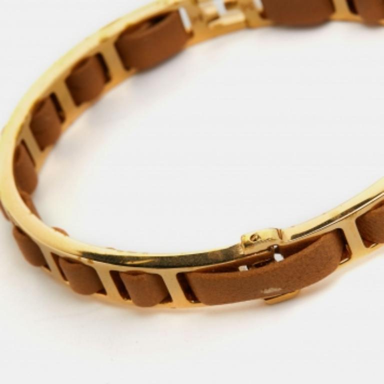Dieses Modell von Fendi wurde aus goldfarbenem Metall gefertigt und mit einem einzelnen Strang aus braunem Leder versehen, der in den Rahmen eingearbeitet ist. Außerdem trägt es das charakteristische F-Logo.