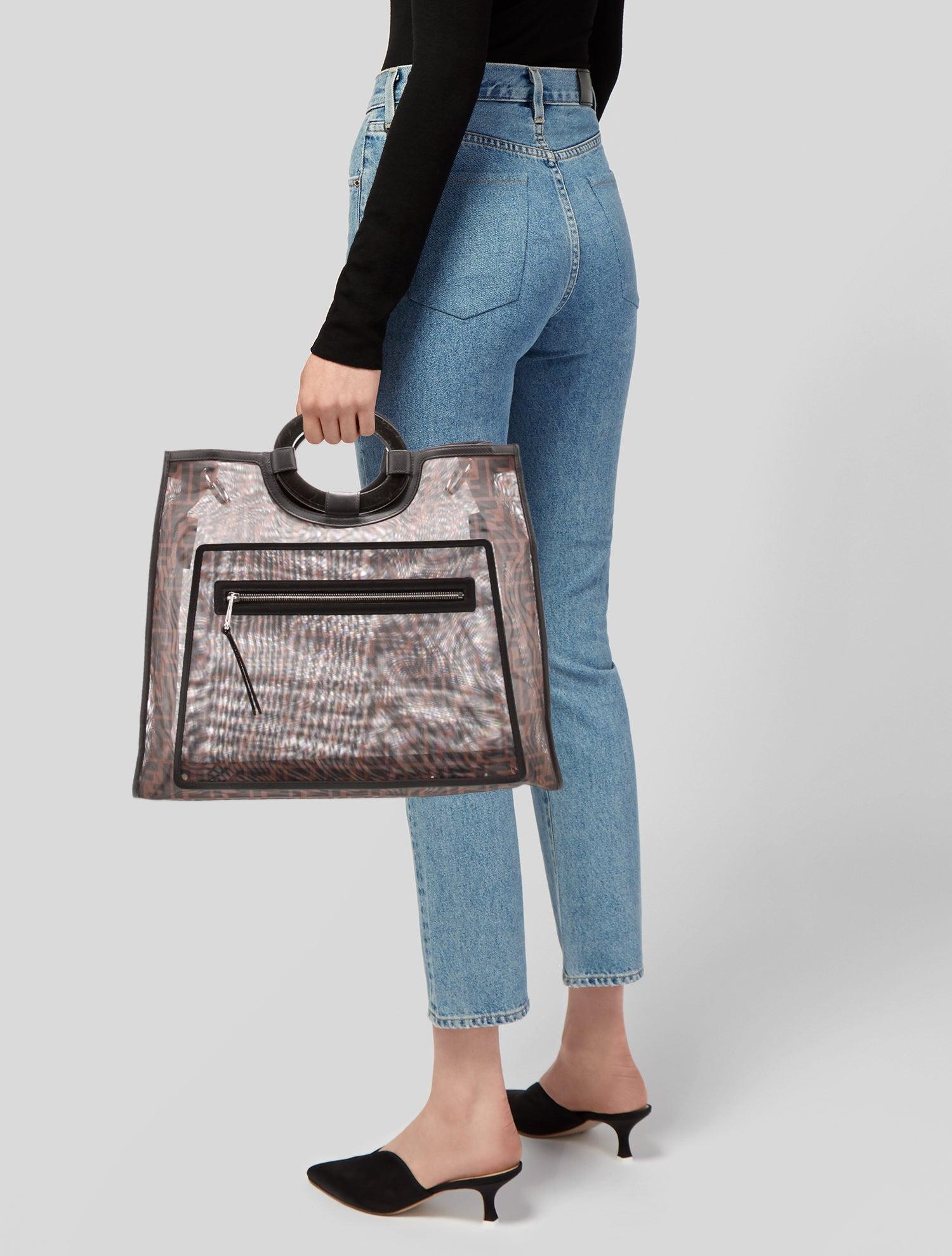 This Fendi top handle bag features transparent PVC construction, white Zucca FF print throughout, gold-tone hardware, leather trim embellishment and is complete with an open top.

Color: transparent with brown print
Material: PVC with leather