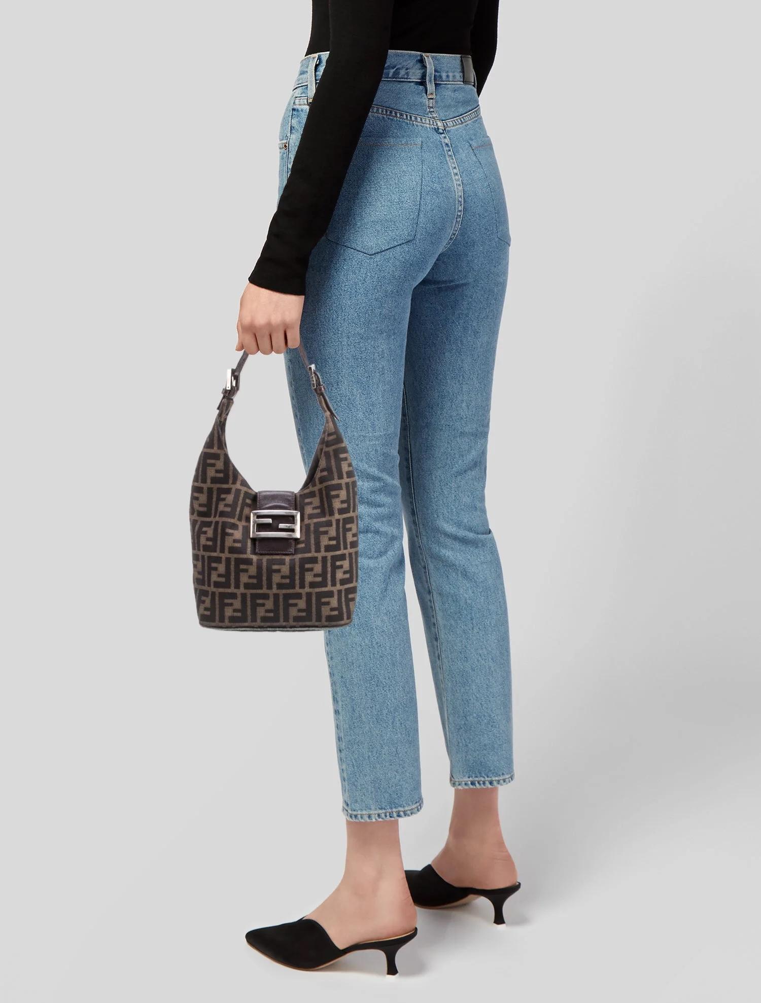 This bag features brown canvas with the Zucca FF logo print, silver-tone hardware, leather trim and a single adjustable shoulder strap. The n exterior pocket with leather trim embellishment, and a the. Bag secures with a snap closure that opens to a