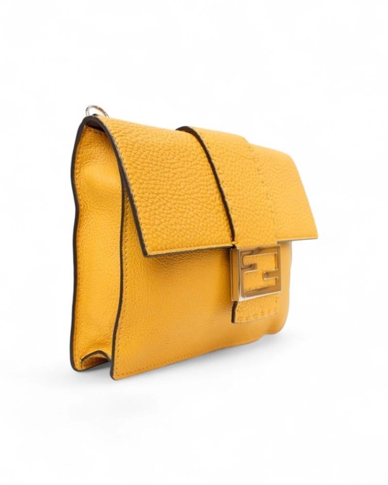 Borsa firmata Fendi, modello Flap Baguette nella misura small, realizzata in pelle gialla con hardware argento. Dotata di una patta con classico logo del brand “FF” in metallo e chiusura calamitata, internamente rivestita in pelle e tela marrone con