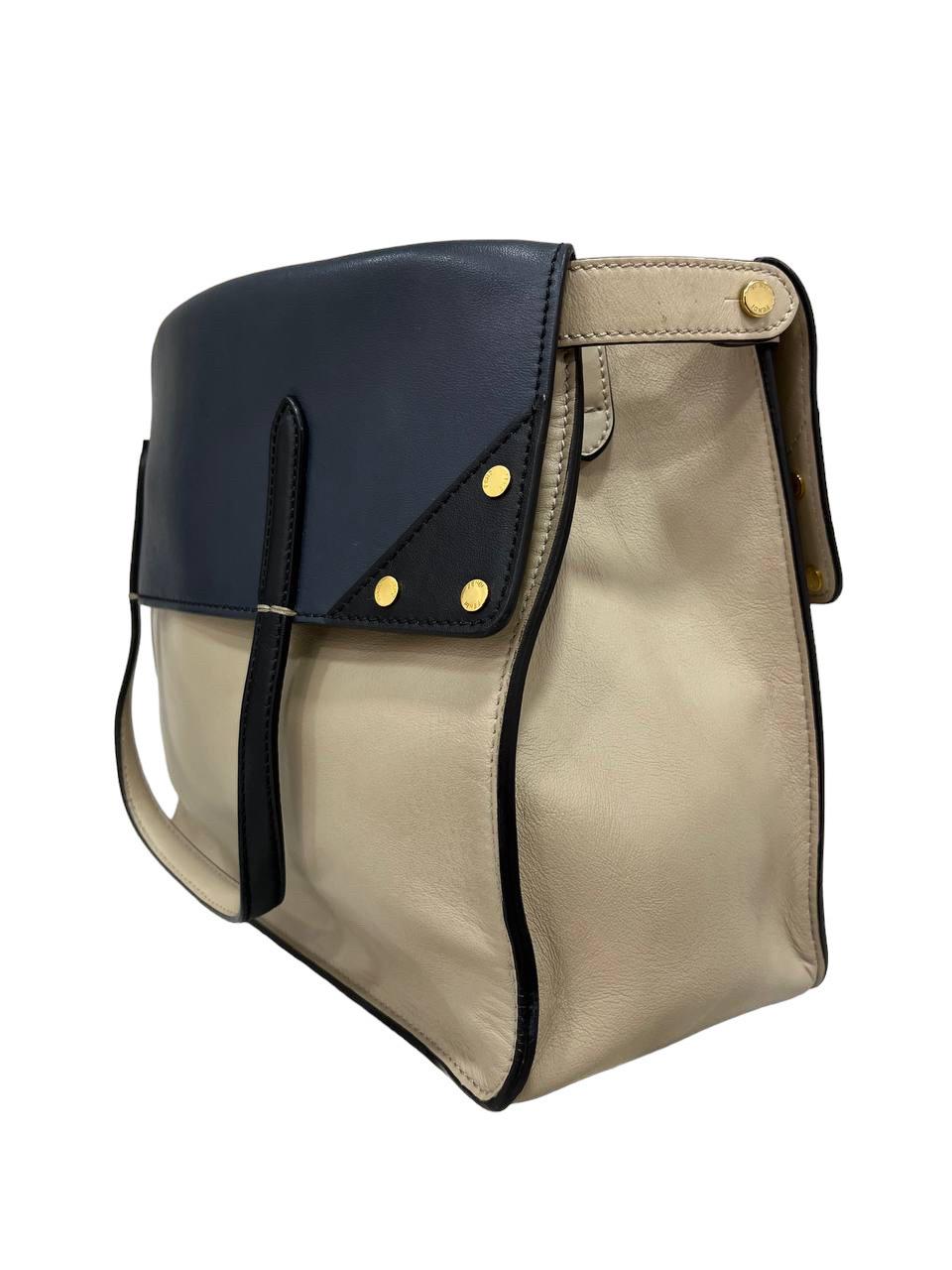 Bag signed Fendi, Flip model, made of beige bicolor leather with blue finishes and gold hardware. Internally lined in suede, quite roomy, it has two flat pockets, one of which has a button closure. It is equipped with two upper handles for carrying