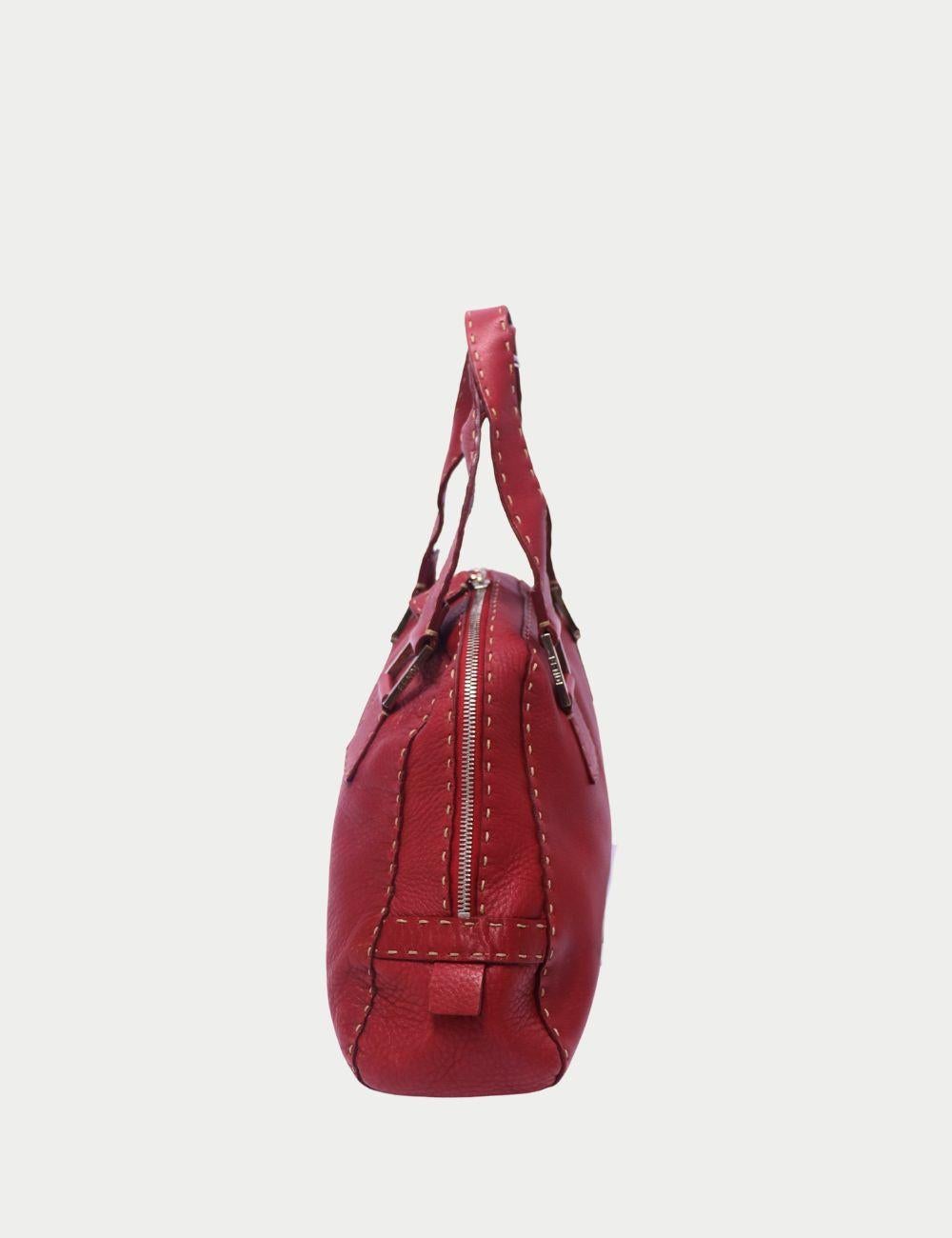 Elevate your accessories edit with this Fendi burgundy leather handbag, a refined yet modern piece that reflects the house’s Italian craftsmanship. Designed in supple grained leather, this bag features contrast oversized stitching and structured top