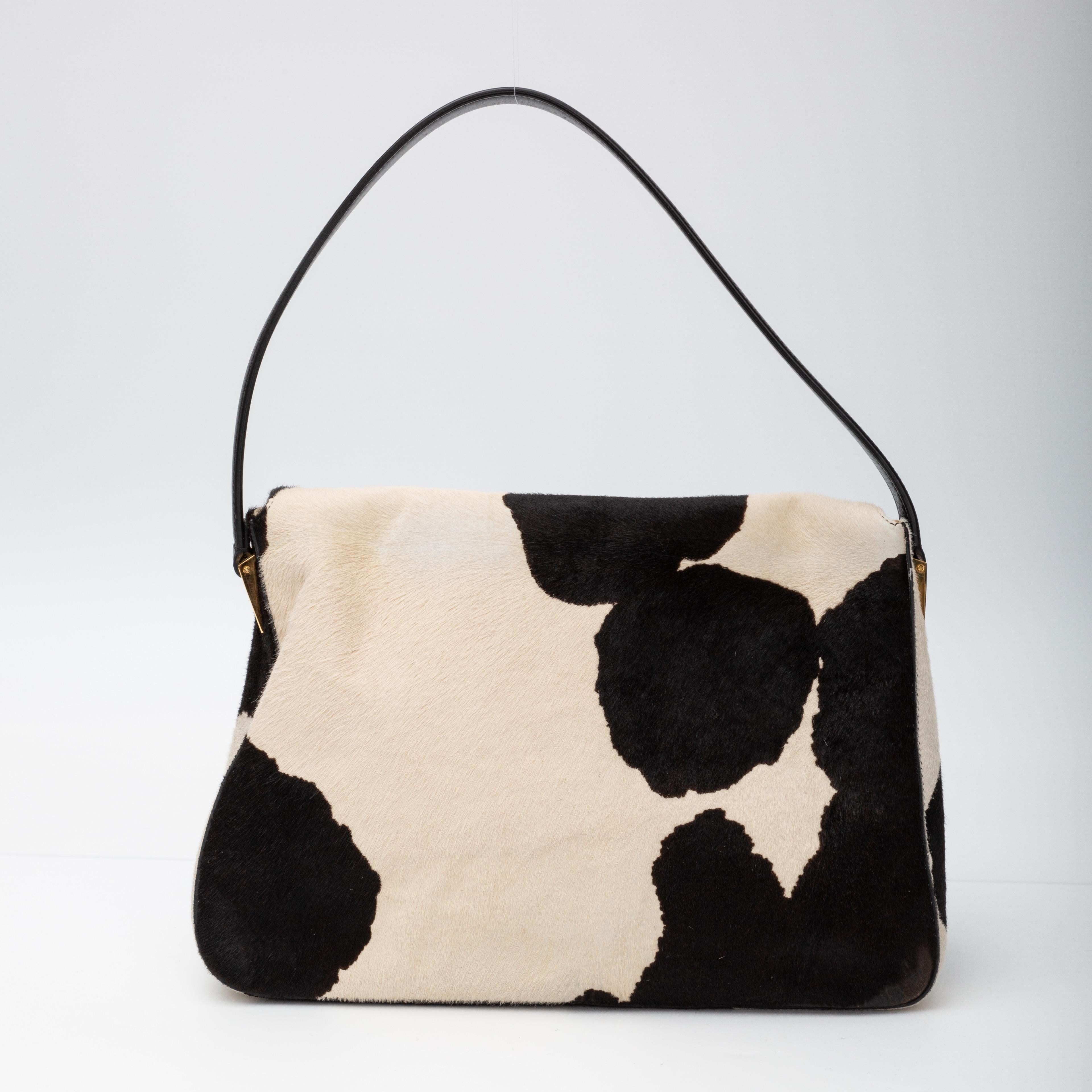 Dieses Mama-Baguette ist aus schwarzem und weißem Kalbshaar mit Kuhdruck gefertigt. Die Tasche hat einen flachen Schulterriemen aus Leder, eine Frontklappe mit einem FF-Detail aus Harz an der Klappschnalle, einen Schnappverschluss und ein