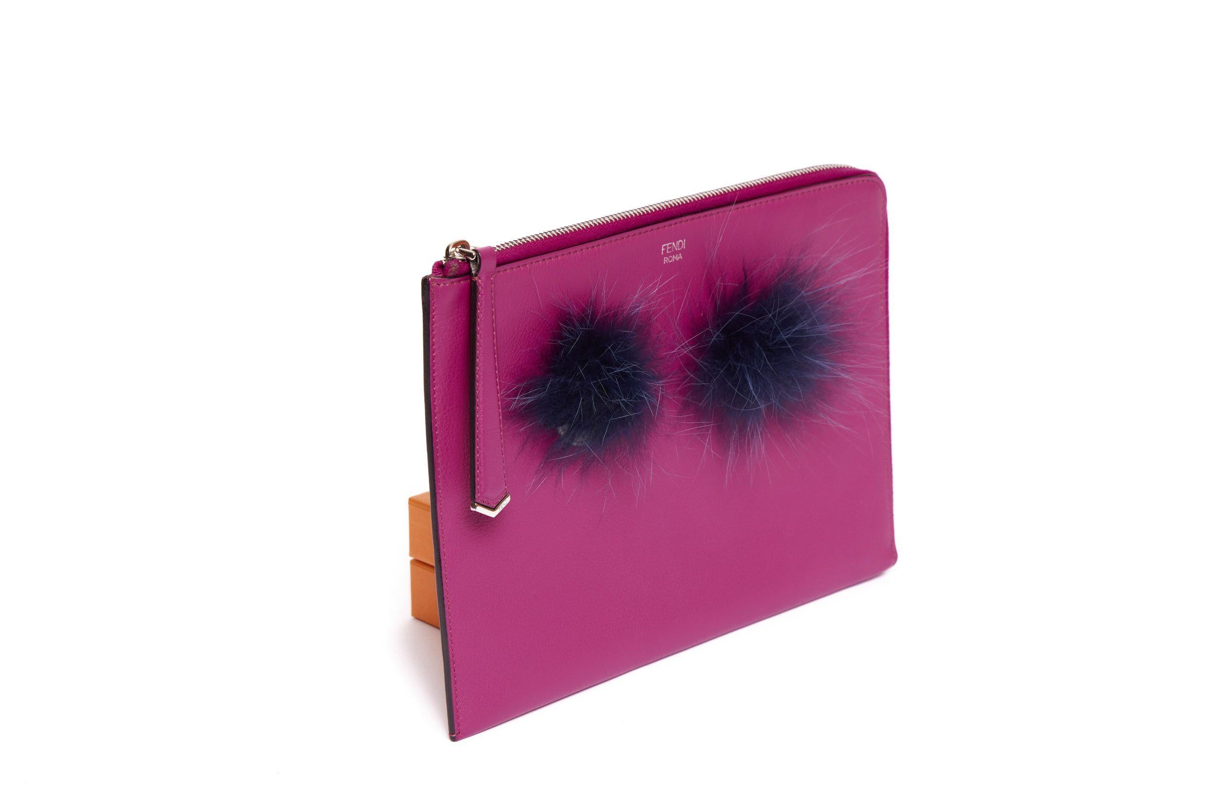 FENDI Fuchsia leather Clutch from the Monster Collection. On front of the clutch are two Monster Eyes motifs crafted of black faux fur. It has a single interior compartment lined with fuchsia canvas and comes with silver metal hardware. The piece