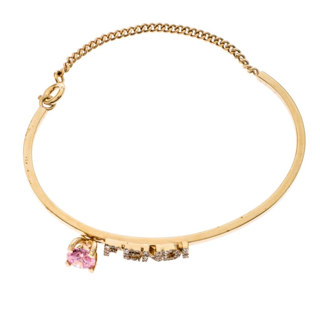 Sometimes, the simplest of designs are the most breathtaking. This minimal bracelet is by Fendi. Crafted from gold-tone metal, it has a crystal-embellished FENDI detail and a pink stone. The bracelet fixes around the wrist with a spring-ring