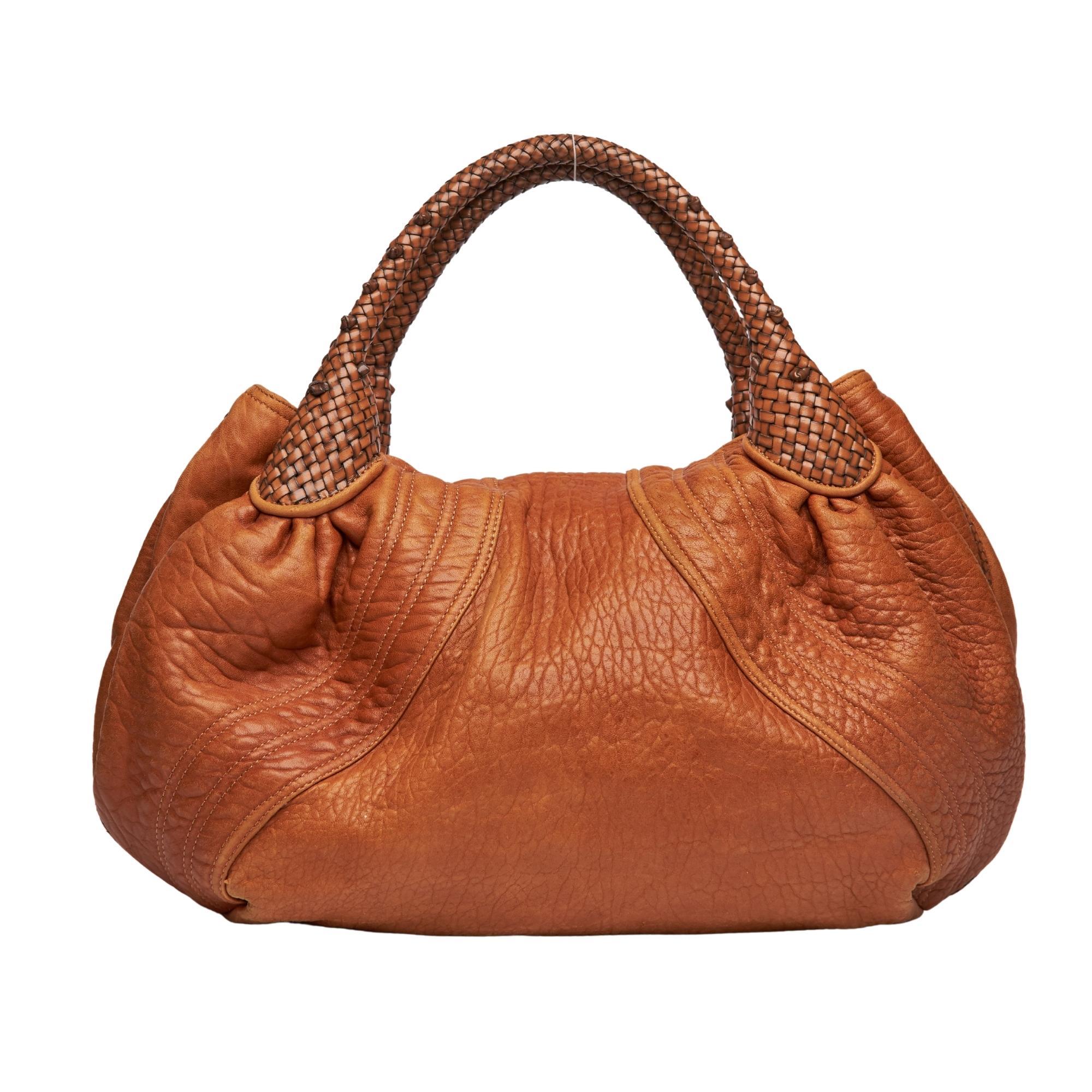 
This signature hobo bag by Fendi is made of rich textured golden brown nappa leather and features a fold over flap with signature wristlet accent, woven handles, gold tone hardware & zucca fabric interior lining. Featuring two secret compartments,