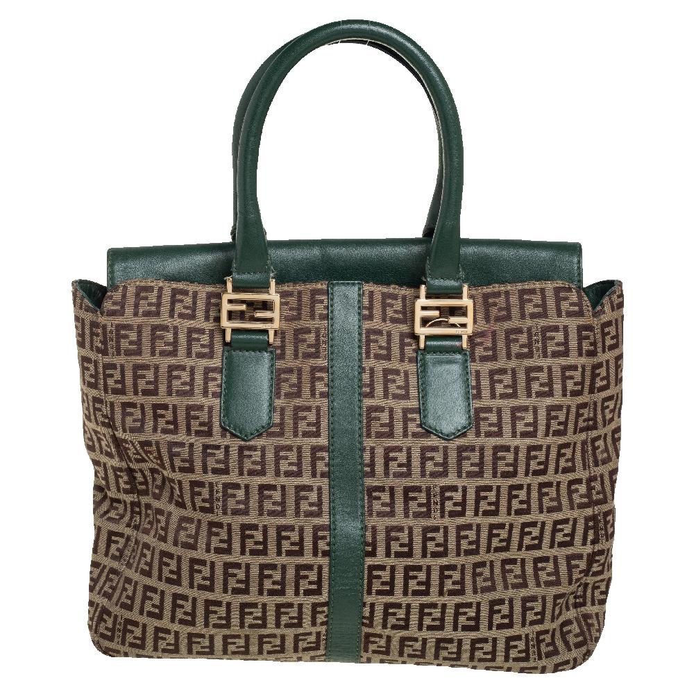 This Fendi tote is trendy and built for everyday use. Crafted from Zucchino canvas, it is contrasted with green-hued leather. The flap opens to a fabric interior spacious enough for your belongings. It is held by dual handles and finished with