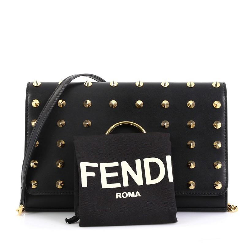 This Fendi Kan I F Wallet On Chain Clutch Studded Leather, crafted from black studded leather, features a chain link with leather strap, Fendi logo at front flap, and gold-tone hardware. Its magnetic snap closure opens to a black leather and fabric