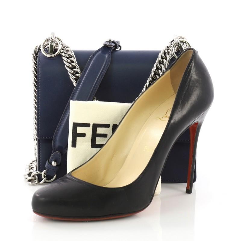 This Fendi Kan I Handbag Leather Small, crafted from navy leather, features flat top handle with studs, long sliding chain-link shoulder strap with leather insert, and silver-tone hardware. Its twist-lock closure opens to a gray microfiber interior