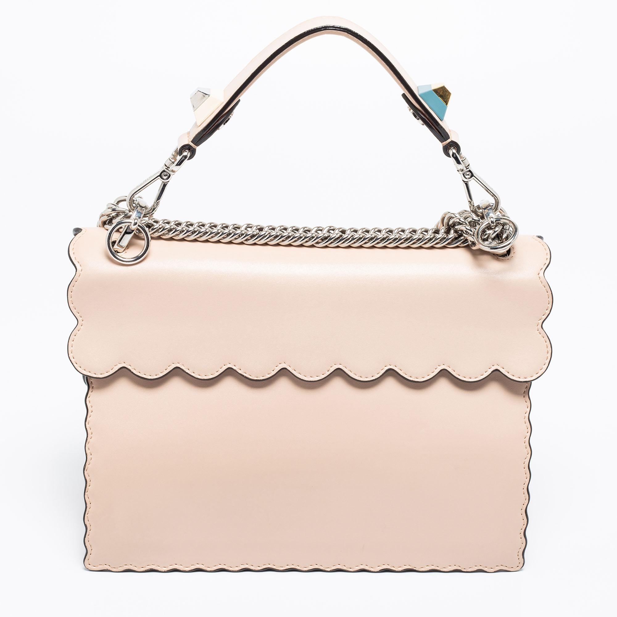 This Kan I Fendi bag exudes an aura of excellence and an unequaled standard of craftsmanship. It has been crafted from leather in a pink shade and styled with studs and scalloped edges. It opens to a spacious suede-lined interior that can graciously