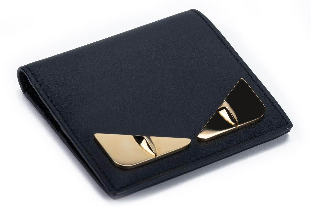 Fendi Monster wallet in black. The briefcase is crafted of leather and on the front are two gold Monster eyes. The interior has several card departments and one bigger department for money. The piece is brand new and comes with a box and dustcover.