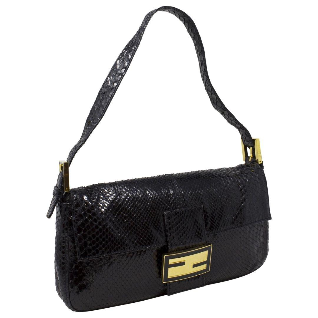 A vintage handbag collector's dream! This Fendi Baguette is sooo special. Rendered in black snakeskin with gold-tone hardware, a single tonal flat shoulder strap with dual buckle adjustments. The magnetic snap closure at the front opens up to a