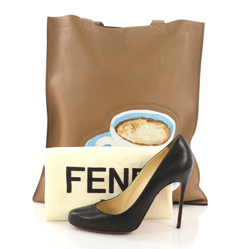 This Fendi Logo Shopper Tote Printed Leather, crafted from brown leather, features dual flat leather handles, multicolored coffee printed logo to the front, and silver-tone hardware. It opens to a taupe microfiber interior with zip pocket. **Note: