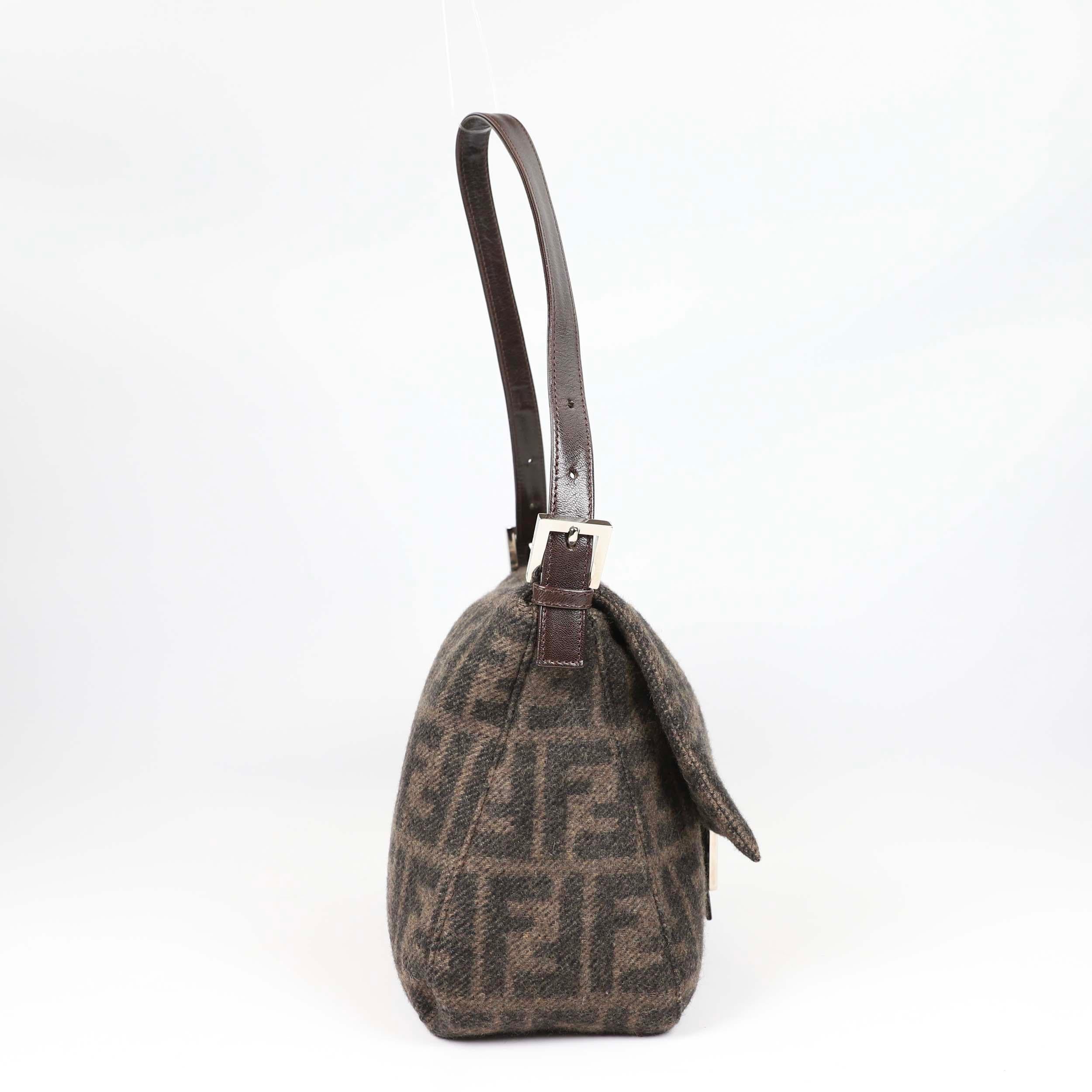 This is a FENDI Mama Baguette in iconic monogram pattern. This chic shoulder bag is made of fine wool. The bag features a detachable leather handle and a Fendi FF logo on the leather strap closure. It opens with a magnetic snap button to a fabric
