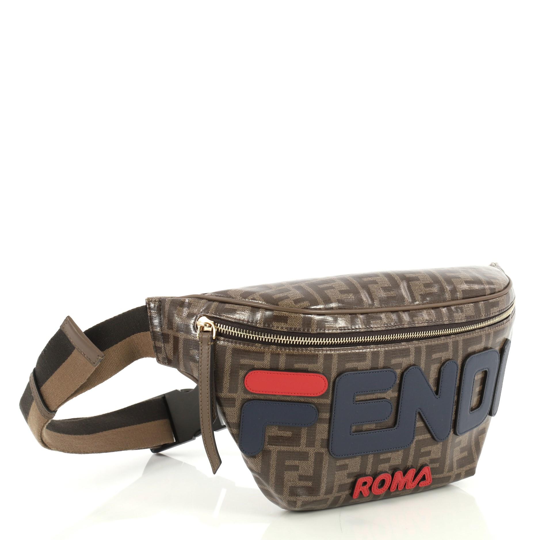 This Fendi Mania Waist Bag Zucca Coated Canvas, crafted from brown zucca coated canvas, features adjustable strap with buckle closure and gold-tone hardware. Its zip closure opens to a brown fabric interior with zip pocket. 

Estimated Retail Price: