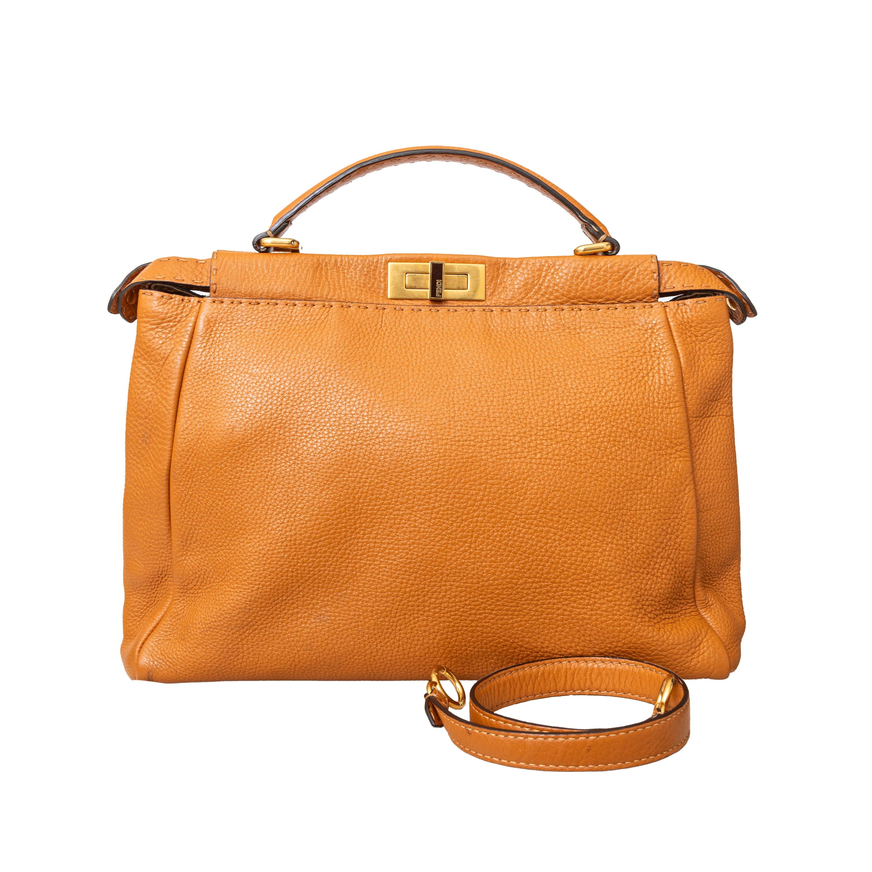The Fendi Medium Peekaboo Bag is a vintage brown leather bag with golden-tone hardware. It features a single rolled handle and tonal lining with two compartments and one interior pocket. Can be carried by hand and as a crossbody with the removable