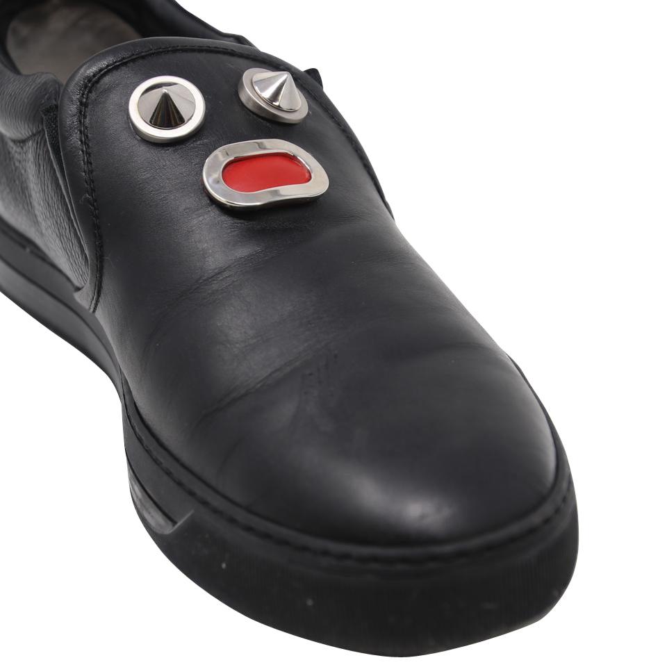 Fendi Hombres Caras Metálicas Piel Zapatillas Slip on Tallas 10

Estas zapatillas bajas de cuero negro de Fendi son el epítome de la moda urbana. Estas zapatillas minimalistas, decoradas con las emblemáticas caras de la marca en metal con acabado