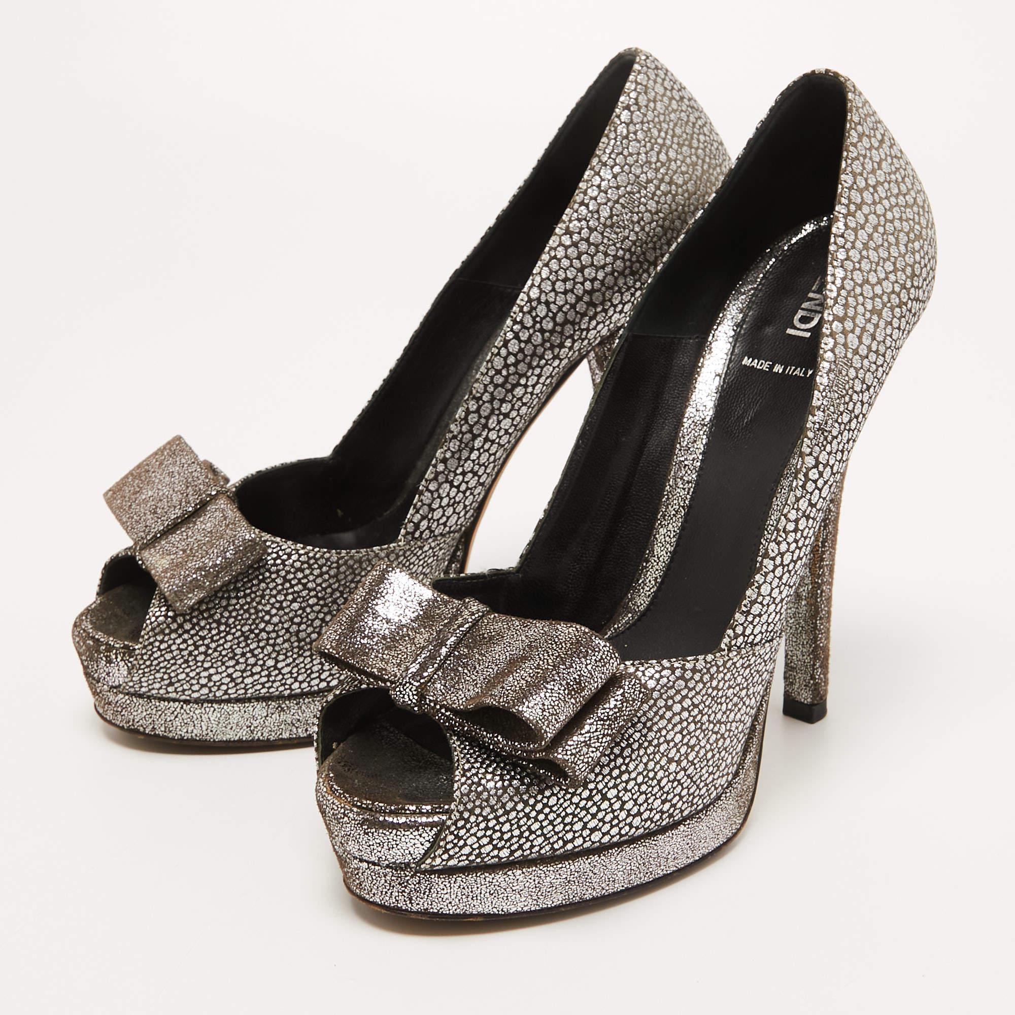 Este par de zapatos de salón de Fendi está confeccionado en tejido brocado con una silueta peep toe y decorado con detalles de lazo. Vienen equipados con cómodas plantillas  Tacones de aguja de 14 cm  y plataformas.