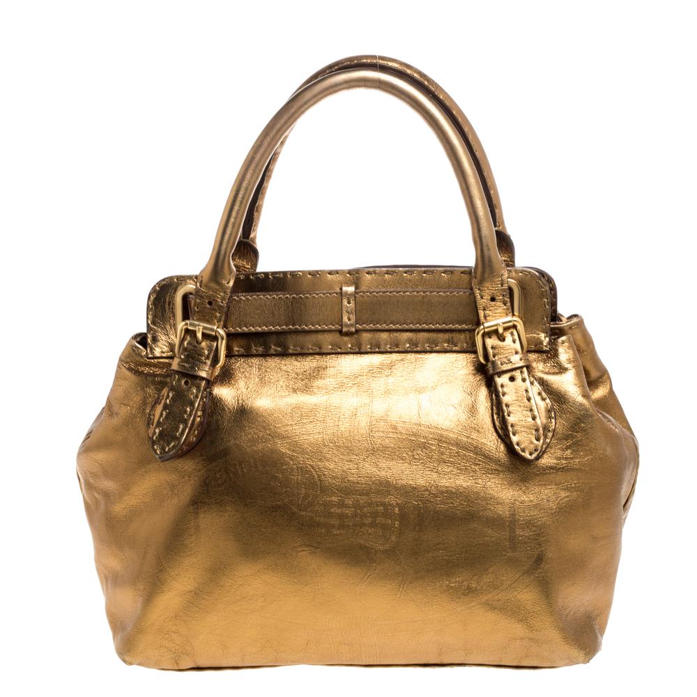 This contemporary satchel by Fendi has been designed to deliver sophistication and glamour. Crafted in Italy, this satchel is made of quality leather and comes in a lovely shade of metallic gold. It is held by dual handles, features a buckled strap