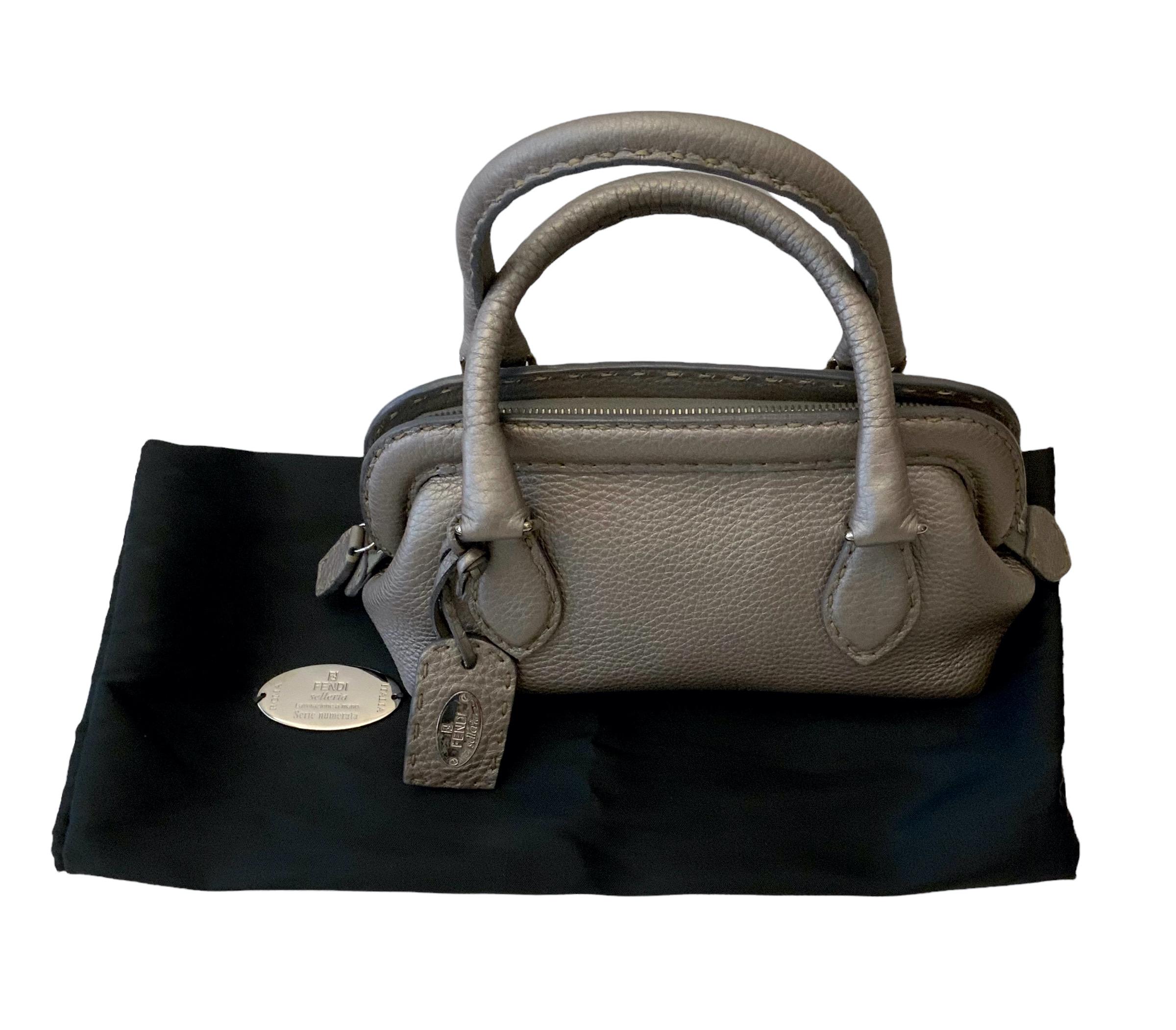 Named after the wife of founder Edoardo Fendi, our pre-owned but as new Mini Adele Bag is crafted of grained calfskin leather in metallic grey taupe color. 
It features hand stitched rolled leather top handles and leather top crest. 
The inside is