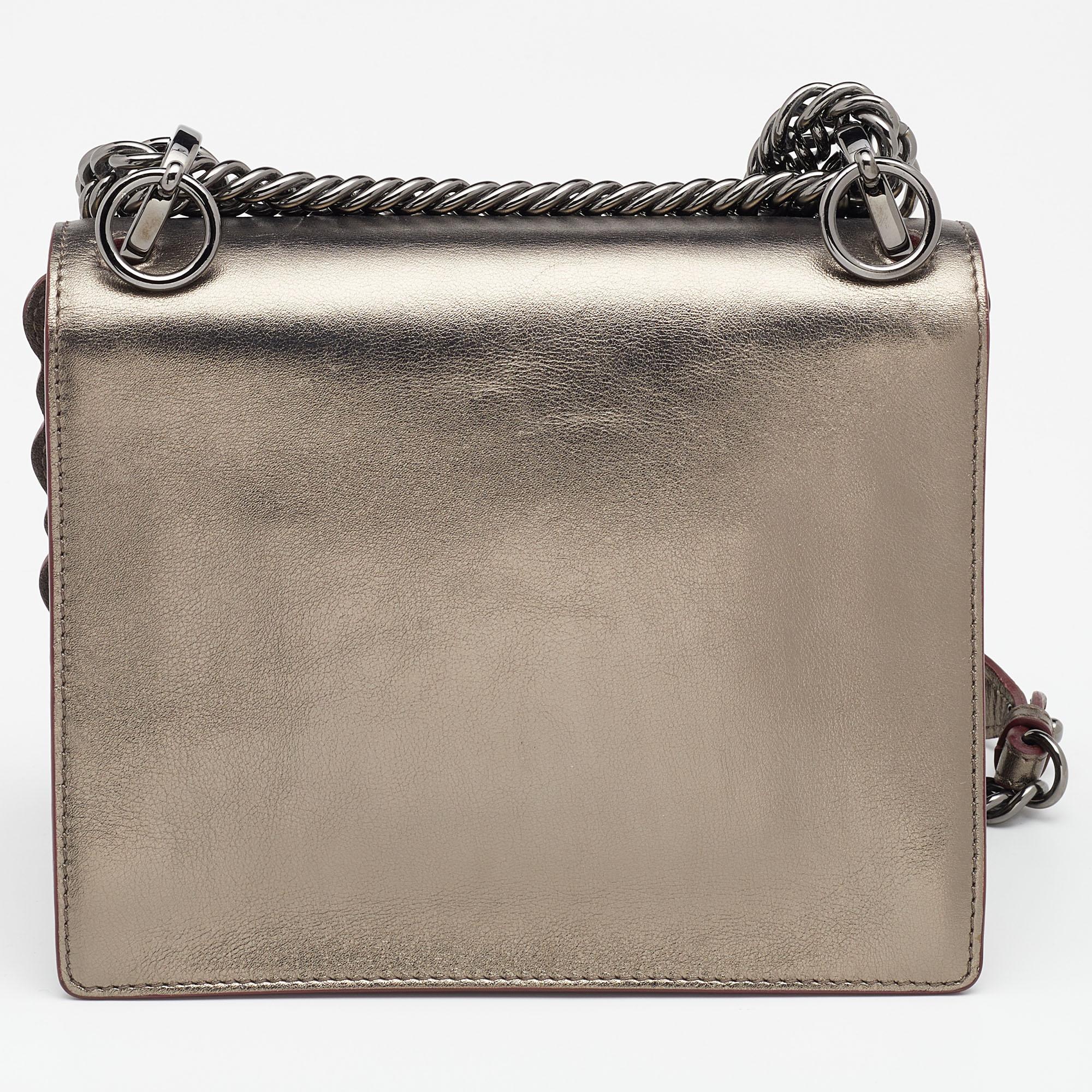 This Kan I shoulder bag from the House of Fendi speaks style and elegance in every way. It has been designed using metallic leather on the exterior. It comes with a sturdy strap, silver-tone hardware, and a spacious suede-lined interior. This