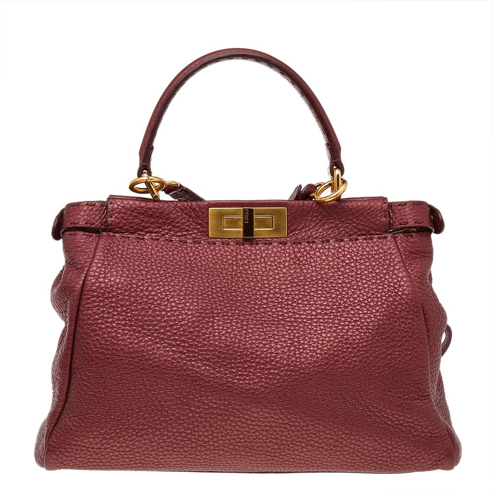This exquisite Peekaboo from Fendi comes meticulously crafted using metallic ruby red leather and is designed with a top handle and shoulder strap. Twist locks in gold-tone metal open to compartments lined with fabric, making us wonder how the bag