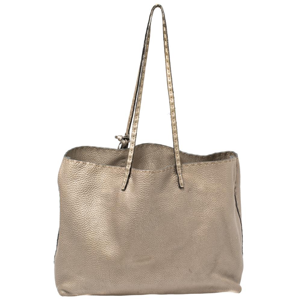 Here's a bag by Fendi that is both stylish and practical. Crafted from Selleria leather in a metallic silver shade, the tote is equipped with a spacious canvas interior wherein you can store more than just your essentials. Hold it by the top handles