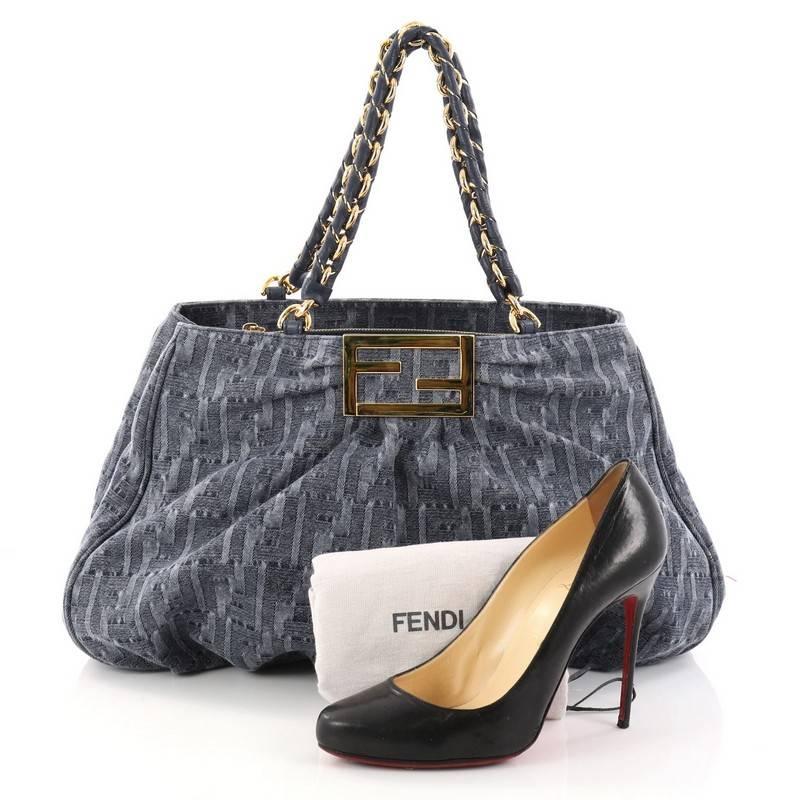 This authentic Fendi Mia Tote Zucca Denim Large is feminine yet edgy in design. Crafted from blue zucca denim, this tote features woven-in leather chain handles, intricate pleating, giant Fendi logo and gold-tone hardware accents. Its wide top
