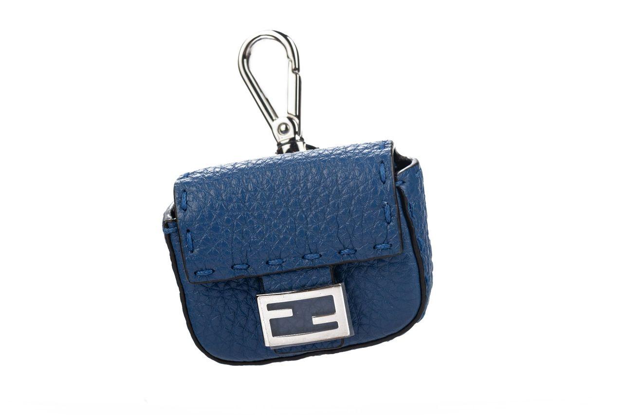 Fendi micro baguette charm in blue. The piece is crafted of leather and has a traditional F logo as a push button to close it. Can be also used as an AirPod case. The item is new and comes with a box and dustcover.