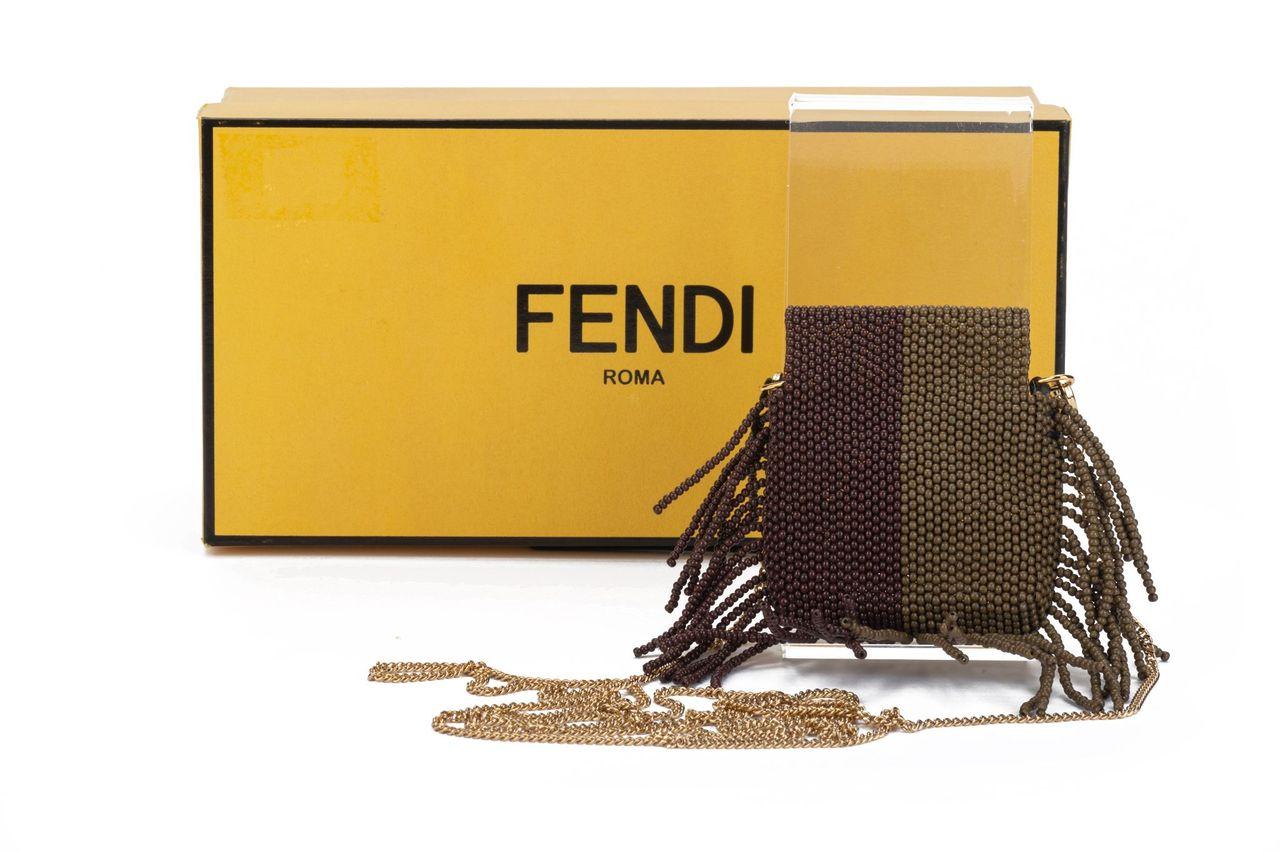 Fendi micro baguette crafted of leather. The item has fringes all around the bag and comes in a tobacco brown. It can be worn as a shoulder bag with the golden detachable chain (23