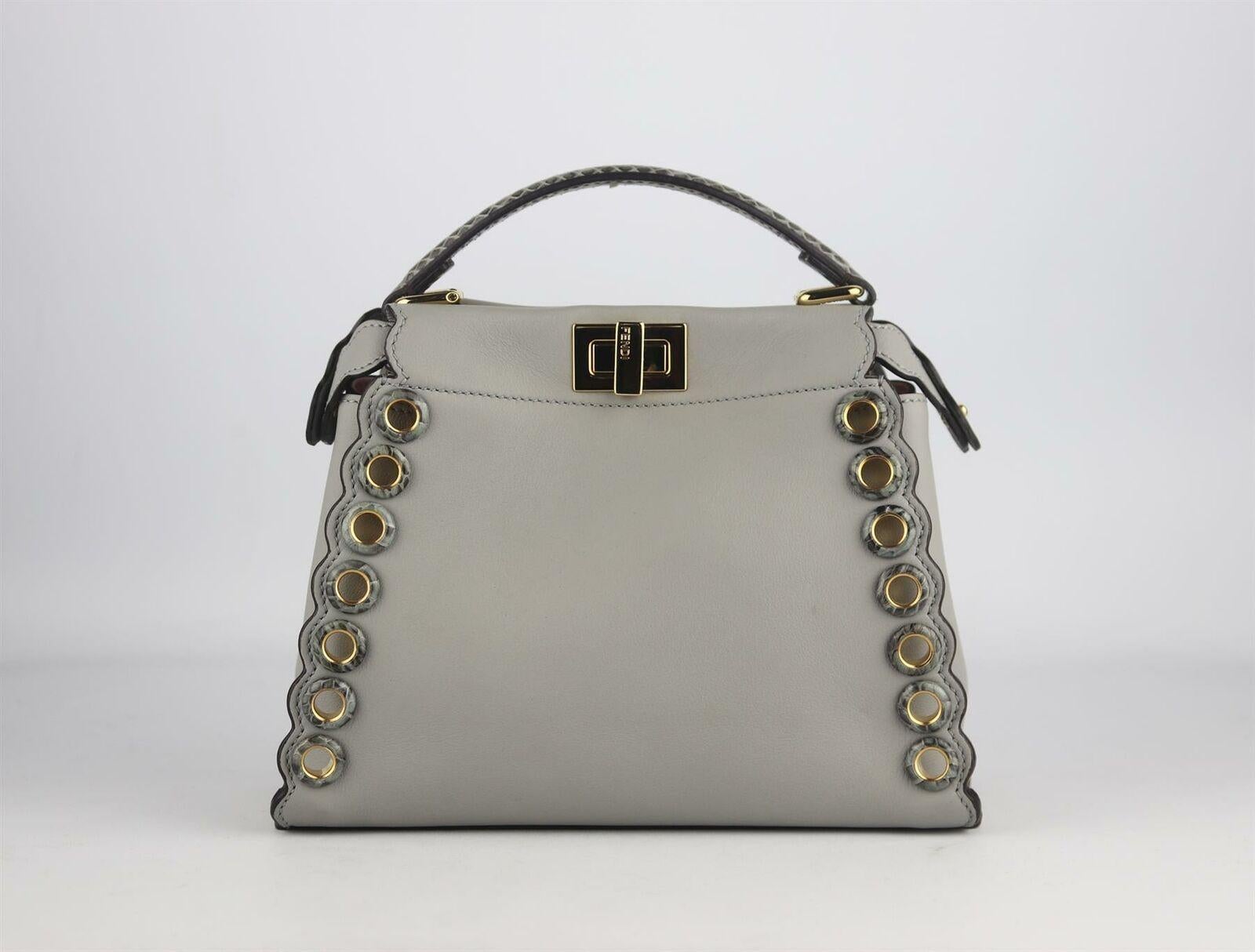 Fendi pares back its coveted 'Peekaboo' bag to mini proportions - it's perfectly sized to fit just the essentials, expertly crafted from smooth light-grey leather and detailed with gold hardware and python trims, it has a baby-pink interior with two