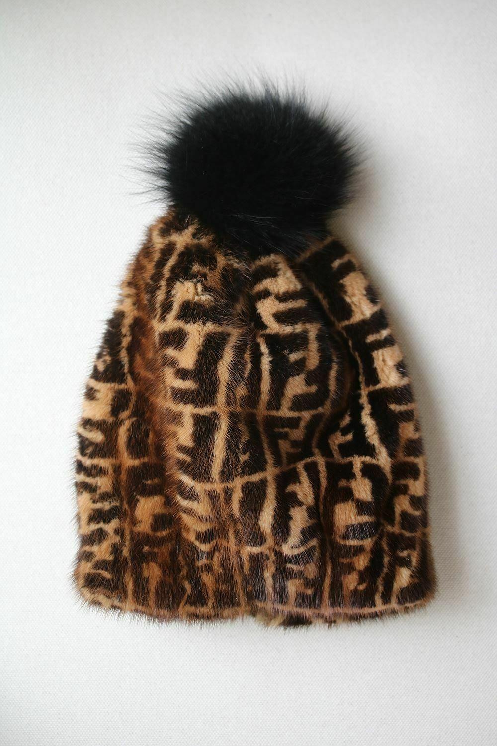 Soft hat made of brown mink fur, printed with a tone-on-tone FF motif. Fox fur pom-pom. Lined in silk. Made in Italy. 100% Mink fur. 100% Fox fur. Lining: 100% silk.

Condition: As new condition, no sign of wear. 
